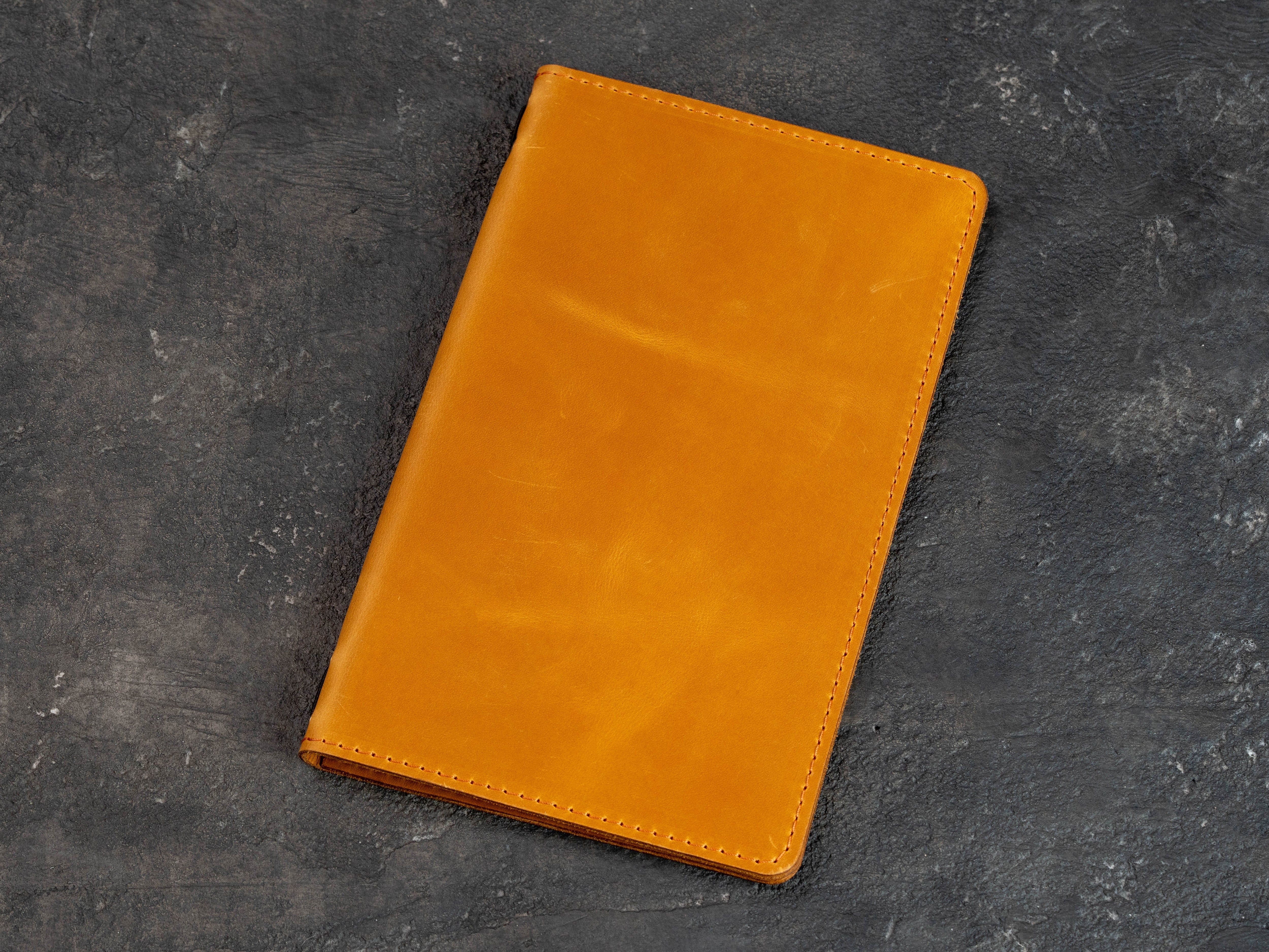 Closed golden yellow leather menu cover shown at an angle on a dark textured background