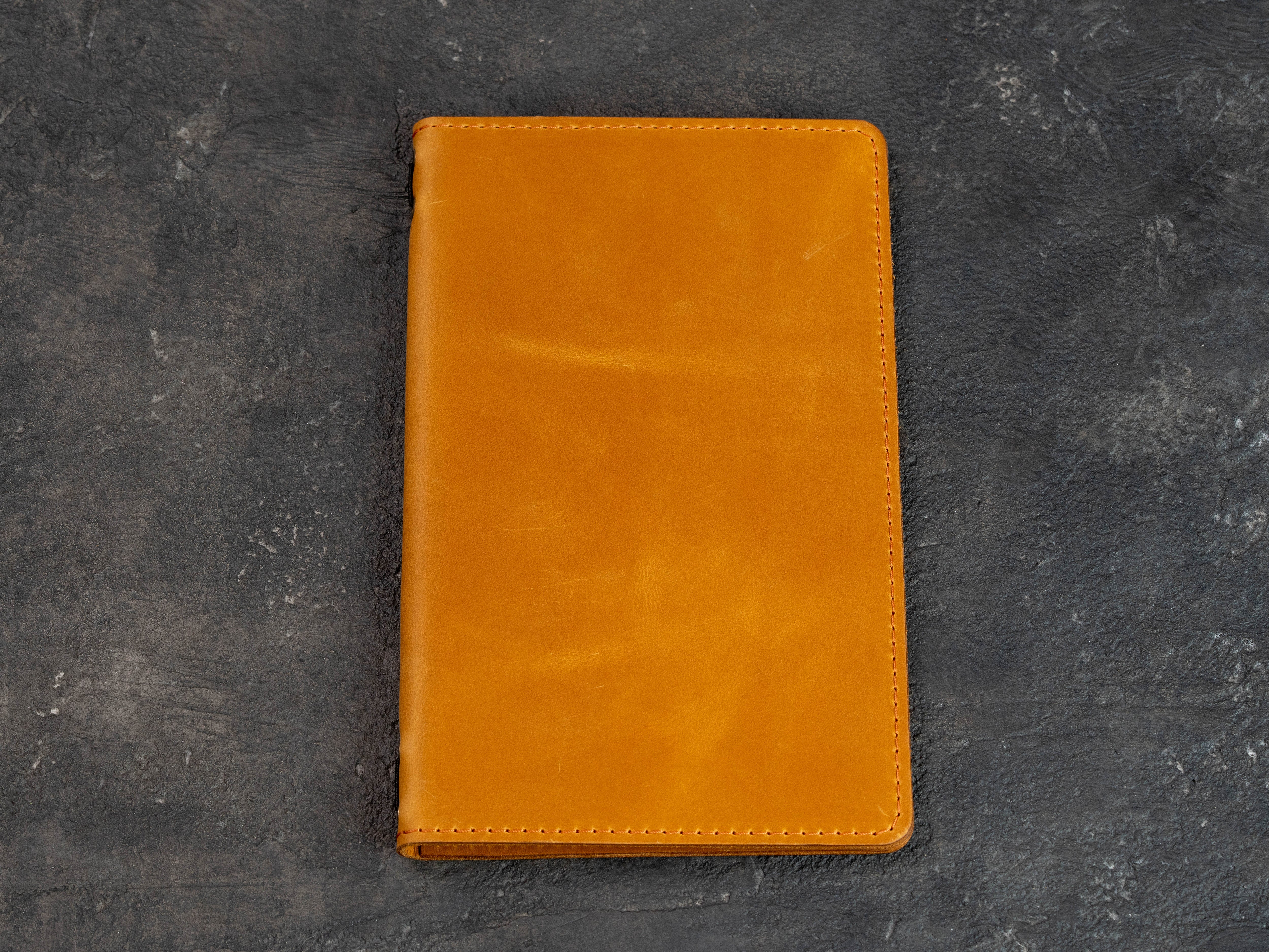 Front view of a closed golden yellow double-layer leather restaurant menu cover