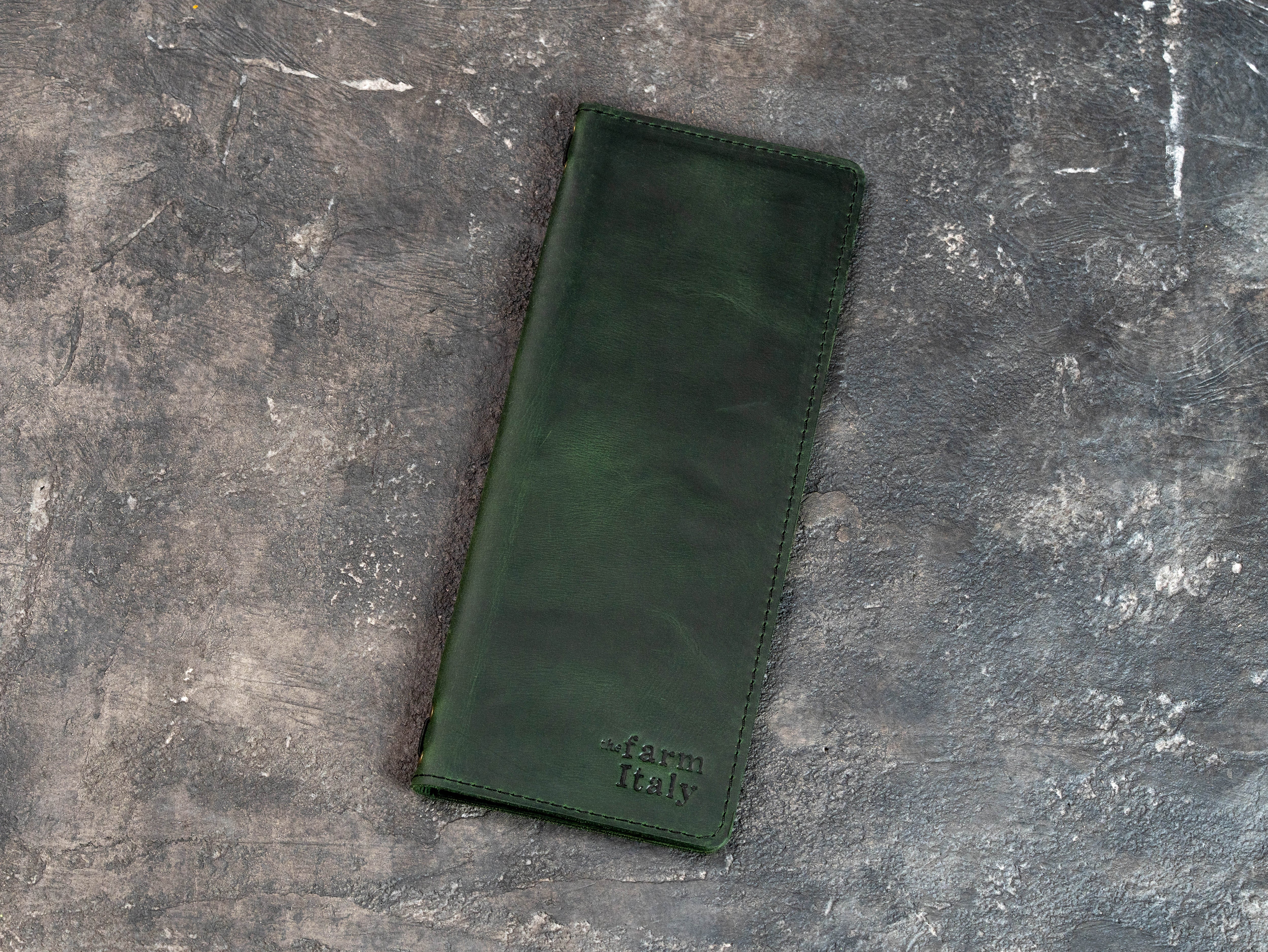 Closed green leather wine and cocktail menu cover with stitched edges and custom embossed logo