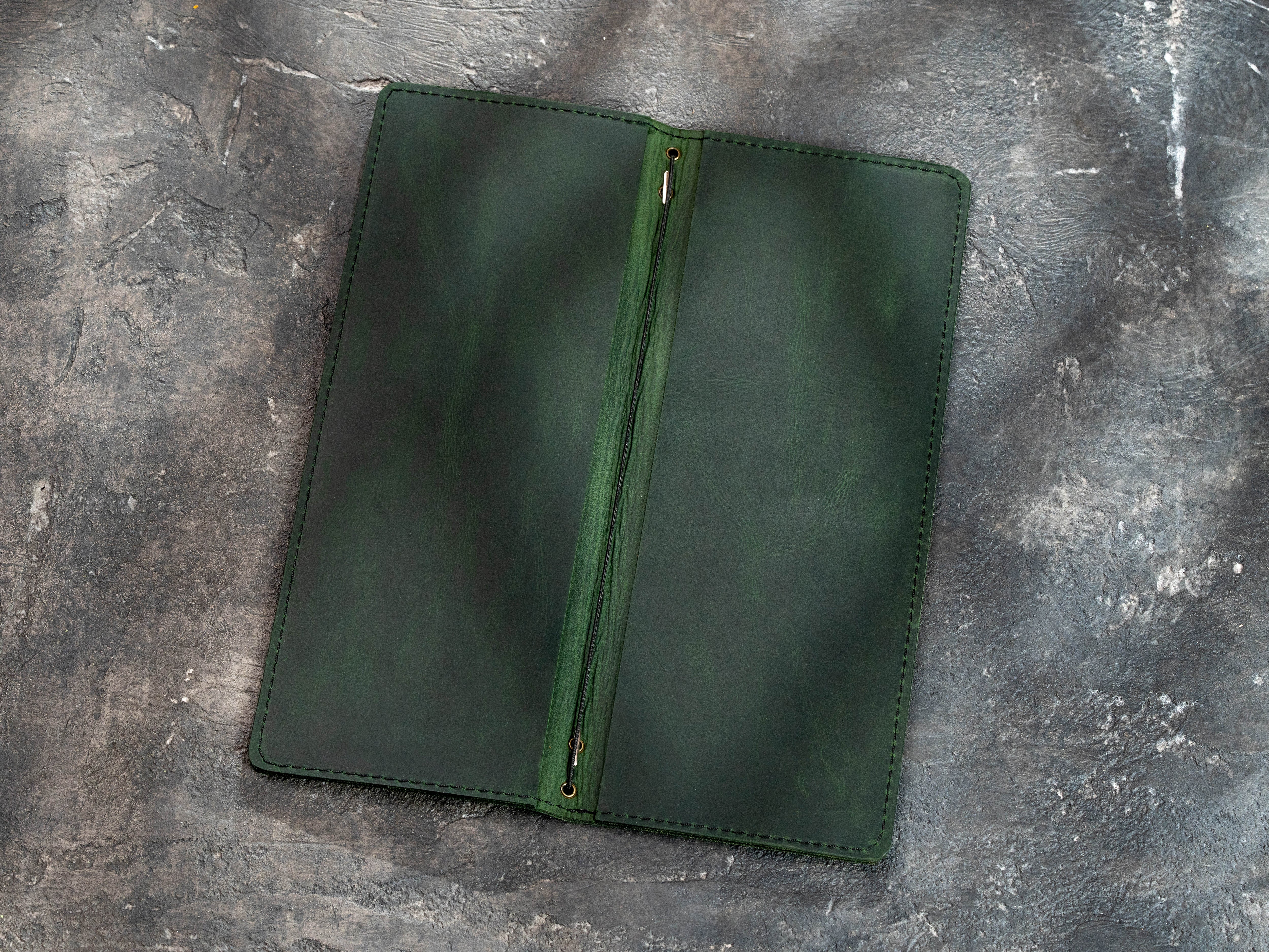 Open green leather menu cover showing double-layer construction and elastic cord binding