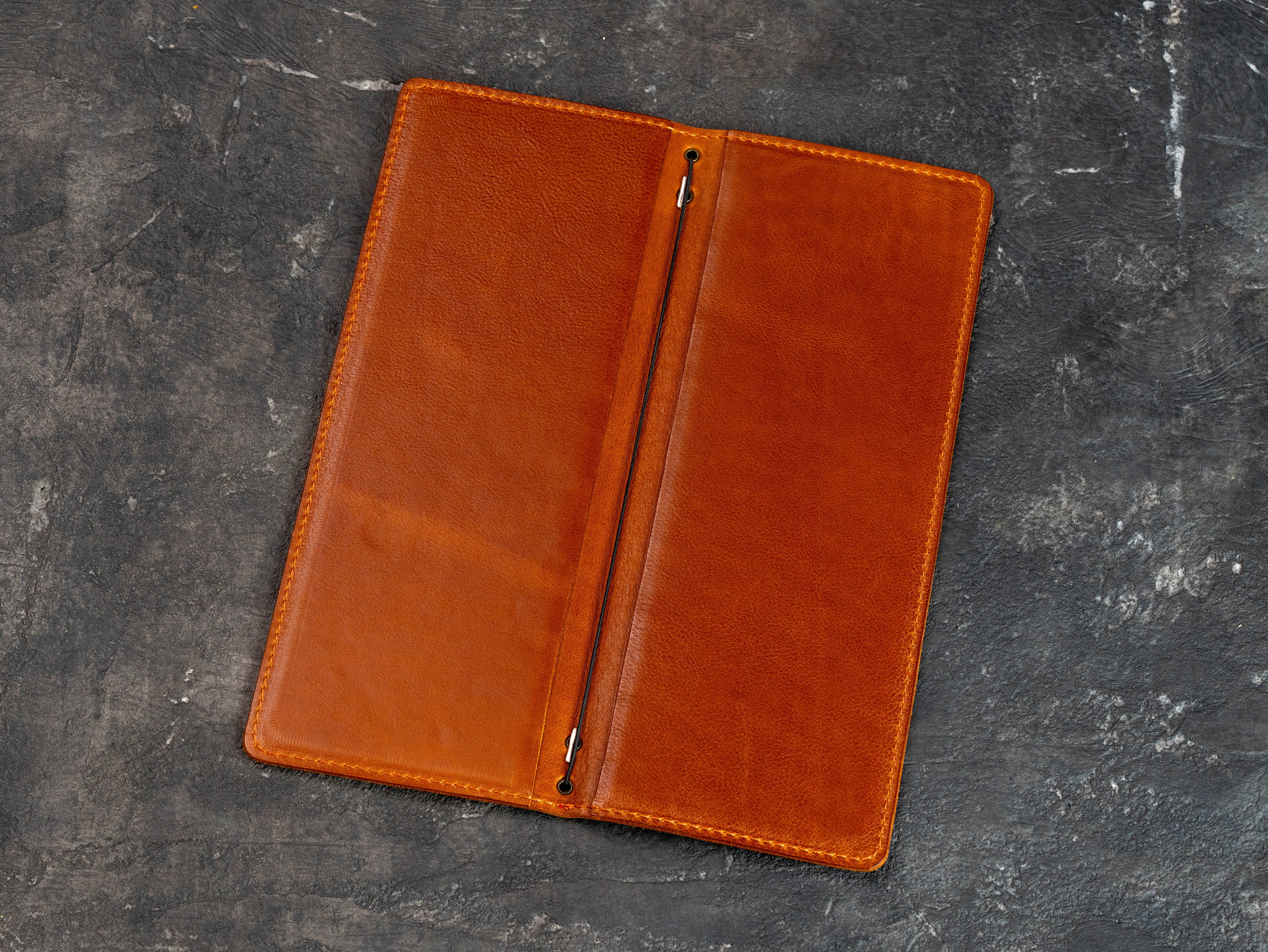 Open cognac leather menu cover showing double-layer construction and central elastic cord binding