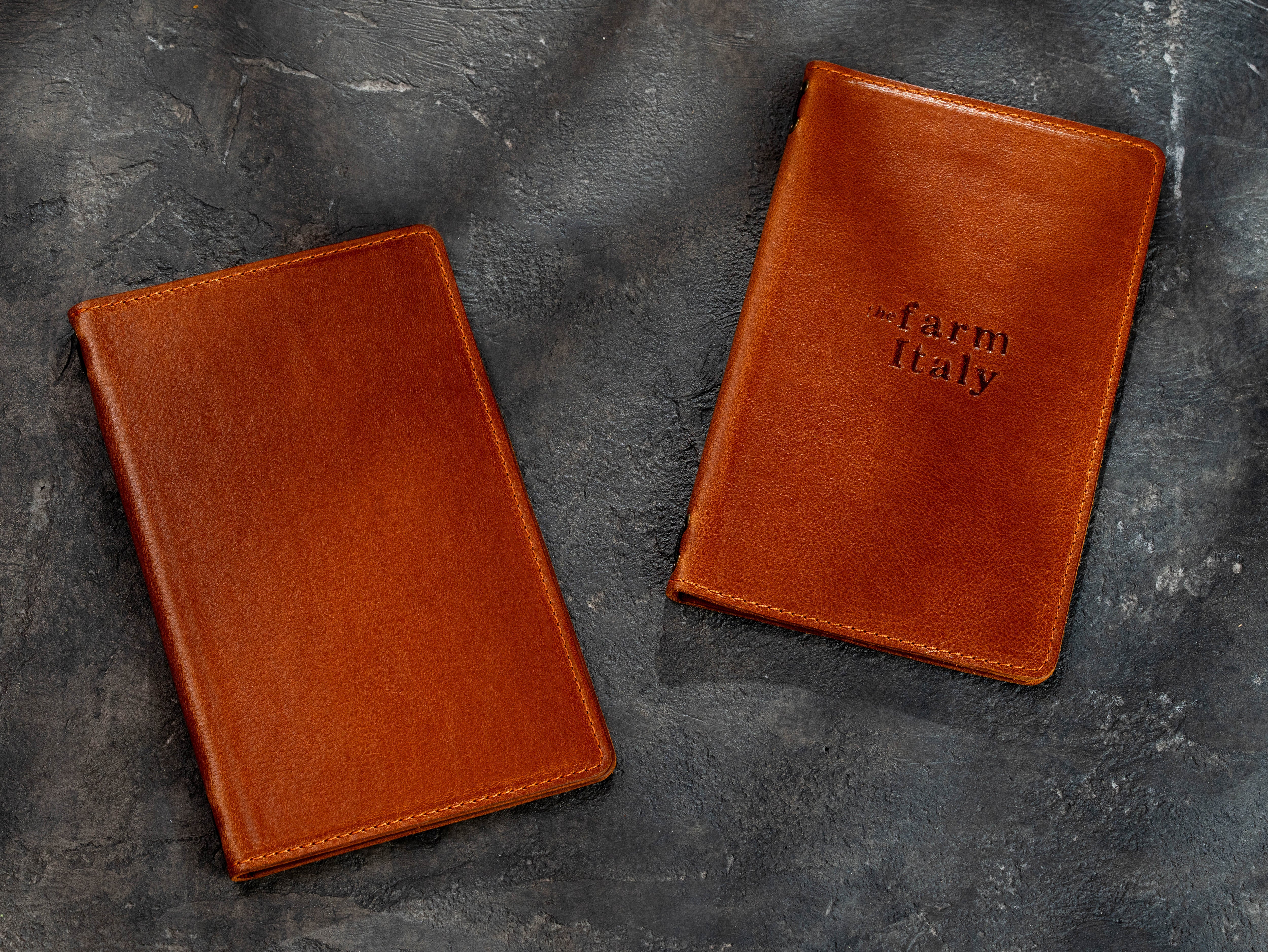 Two camel leather restaurant menu covers shown closed, one with a custom embossed logo