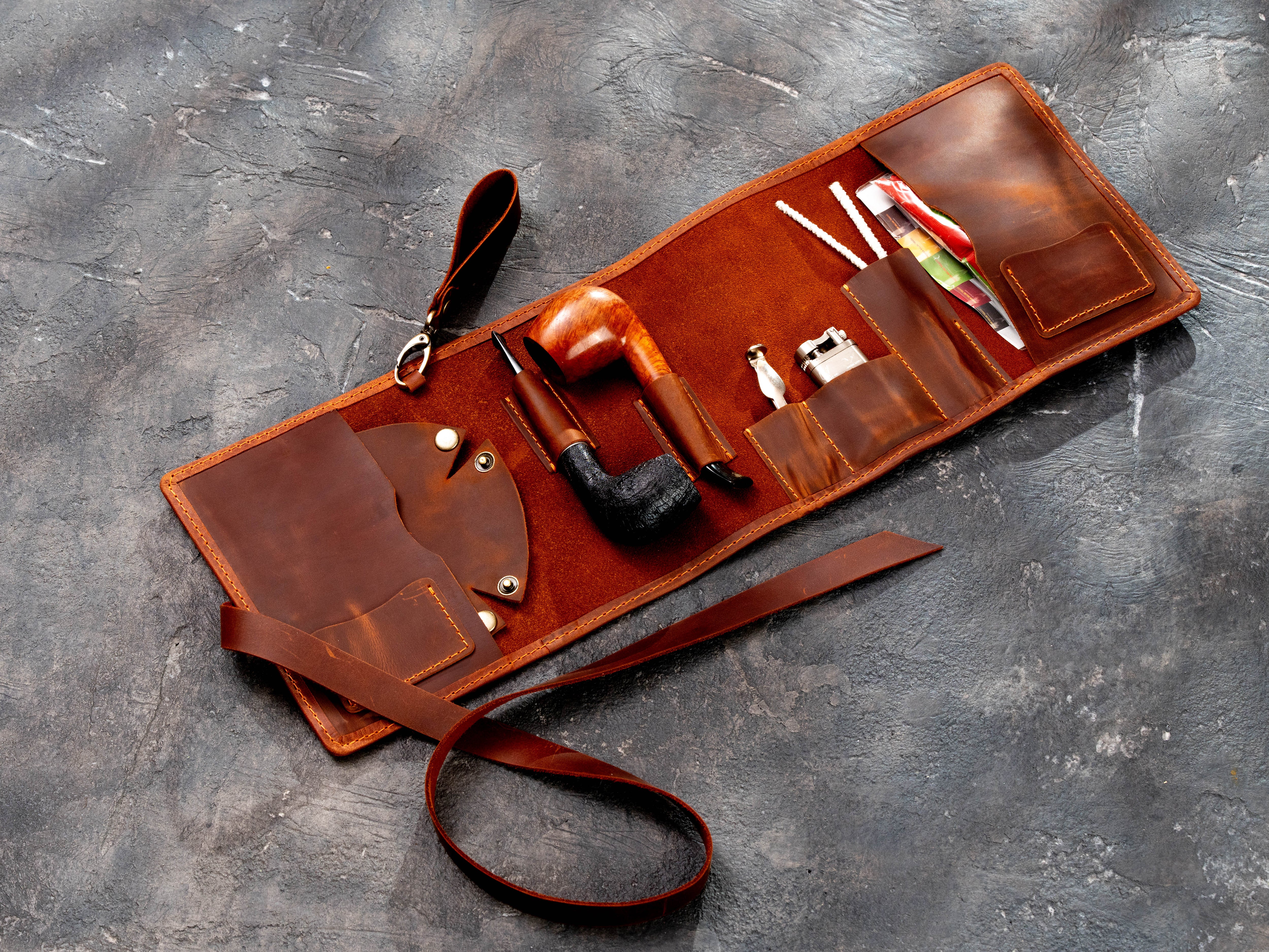 Open copper leather smoking pipe organizer roll with multiple pockets, pipe holders, and a long closing strap