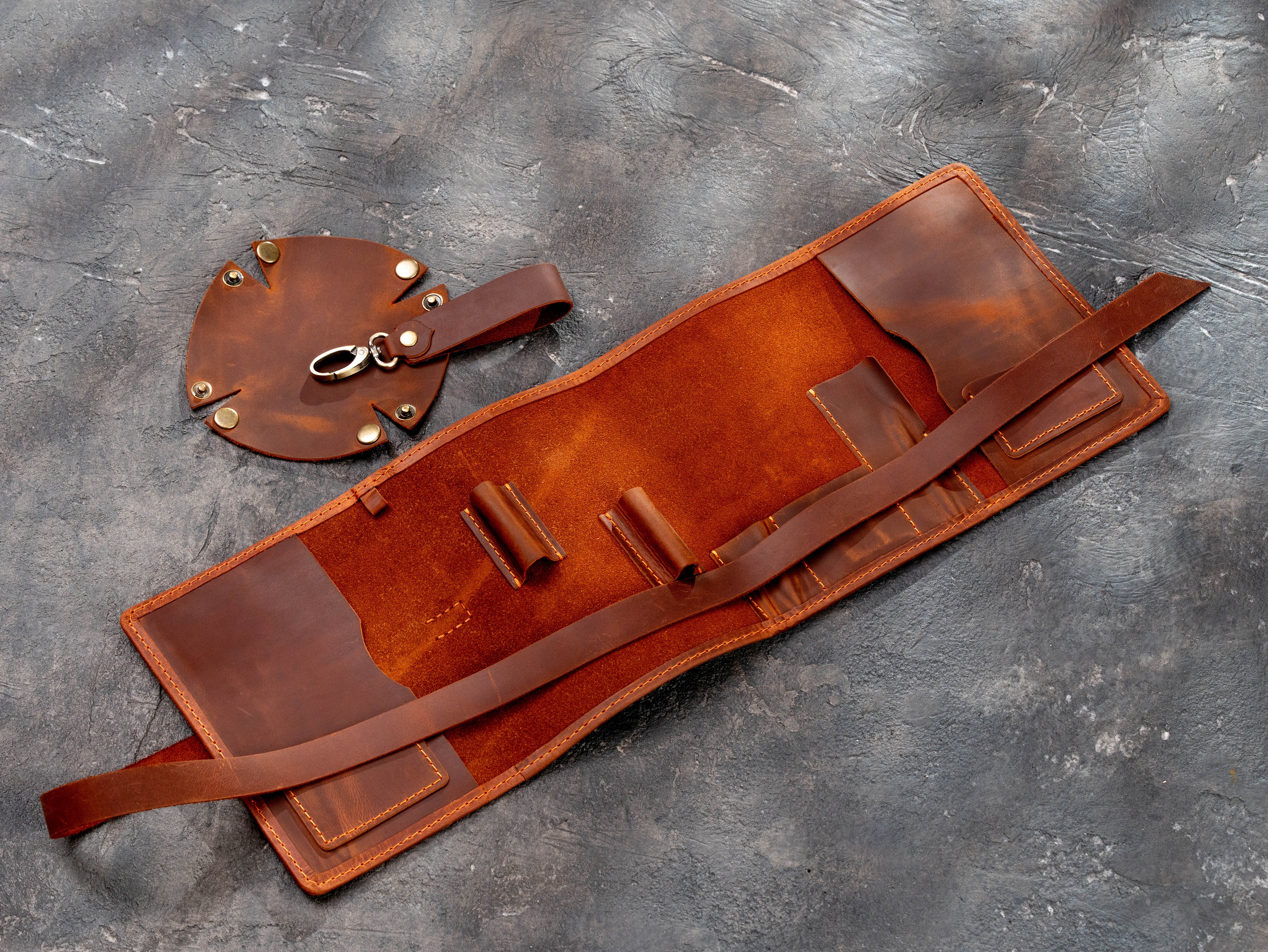 Open copper leather pipe organizer showing interior holders, pockets, removable round stand, and closing strap