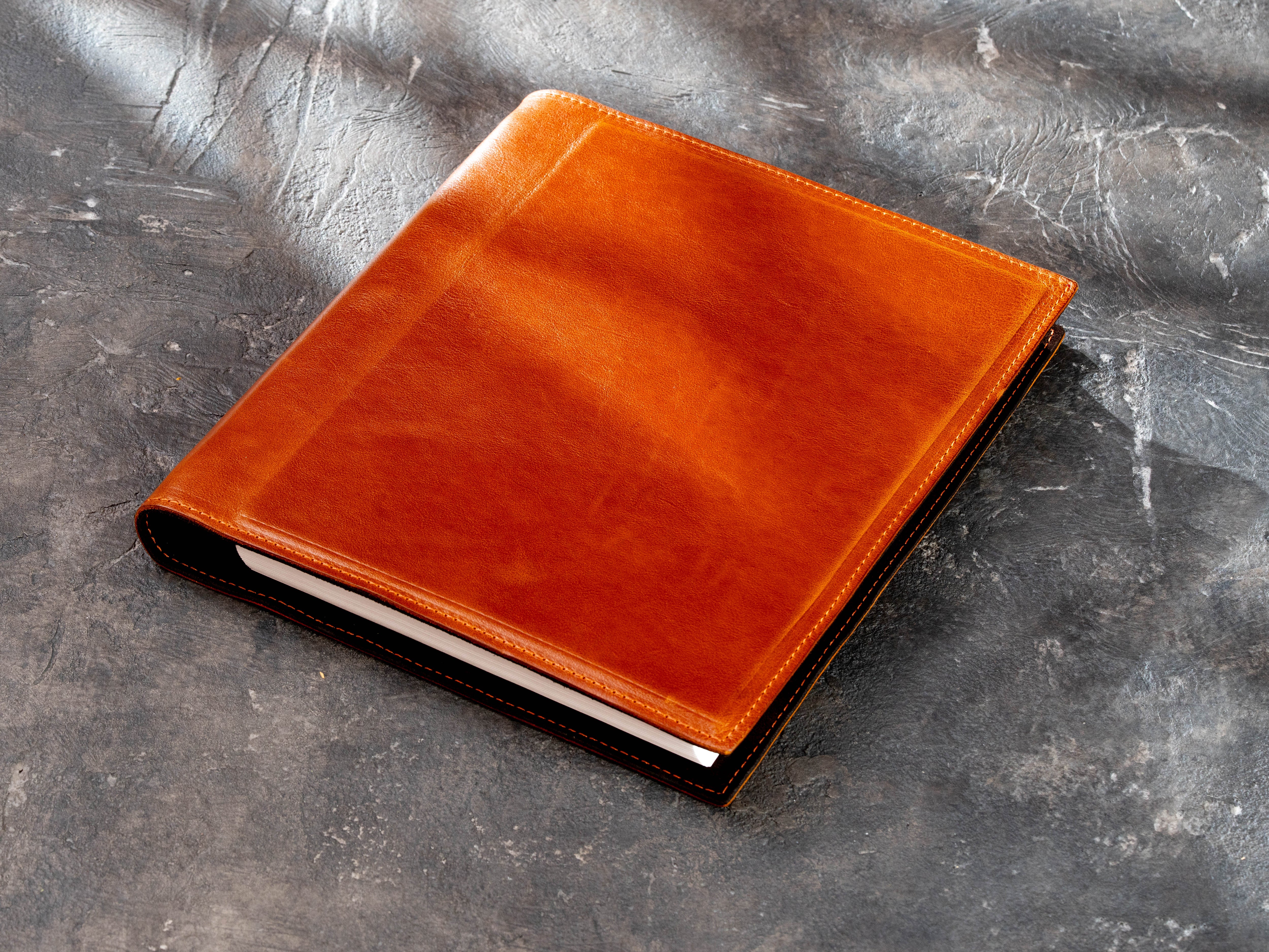Camel leather 3-ring binder folder shown at an angle with stitched edges and rigid construction
