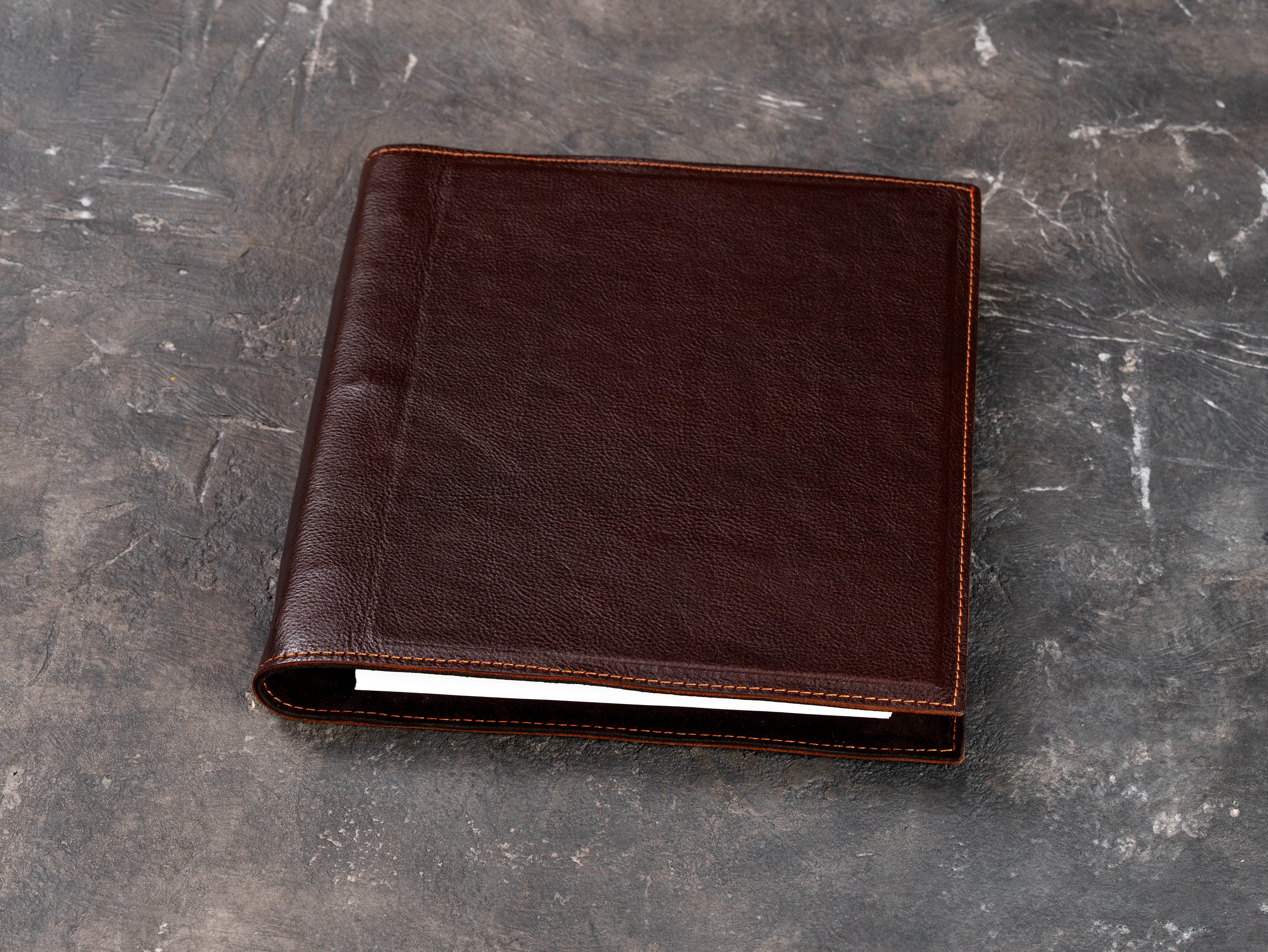 Personalized dark brown leather binder with a custom embossed company logo on the front