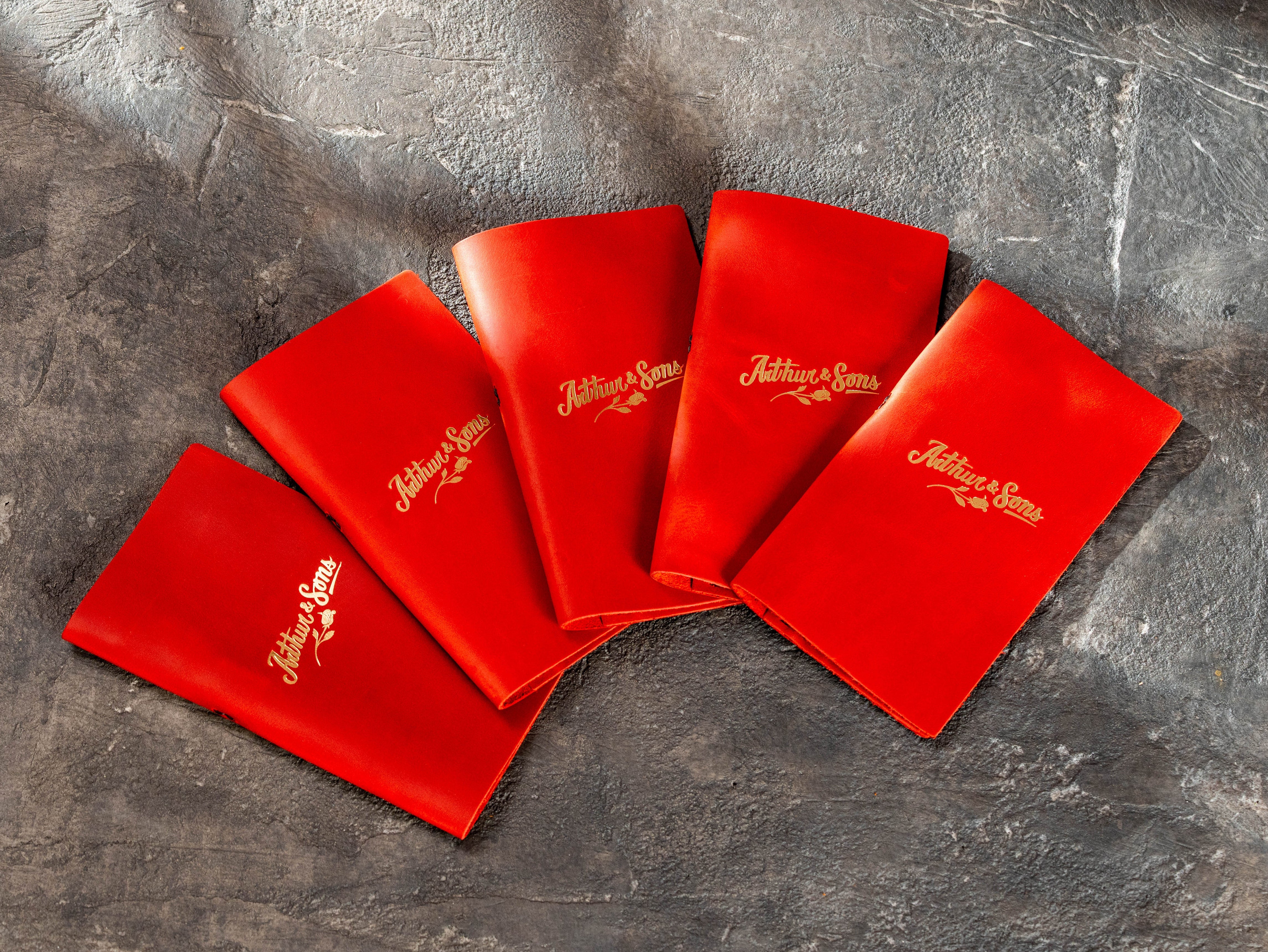 Red leather restaurant check presenters with gold custom logo made for Arthur & Sons
