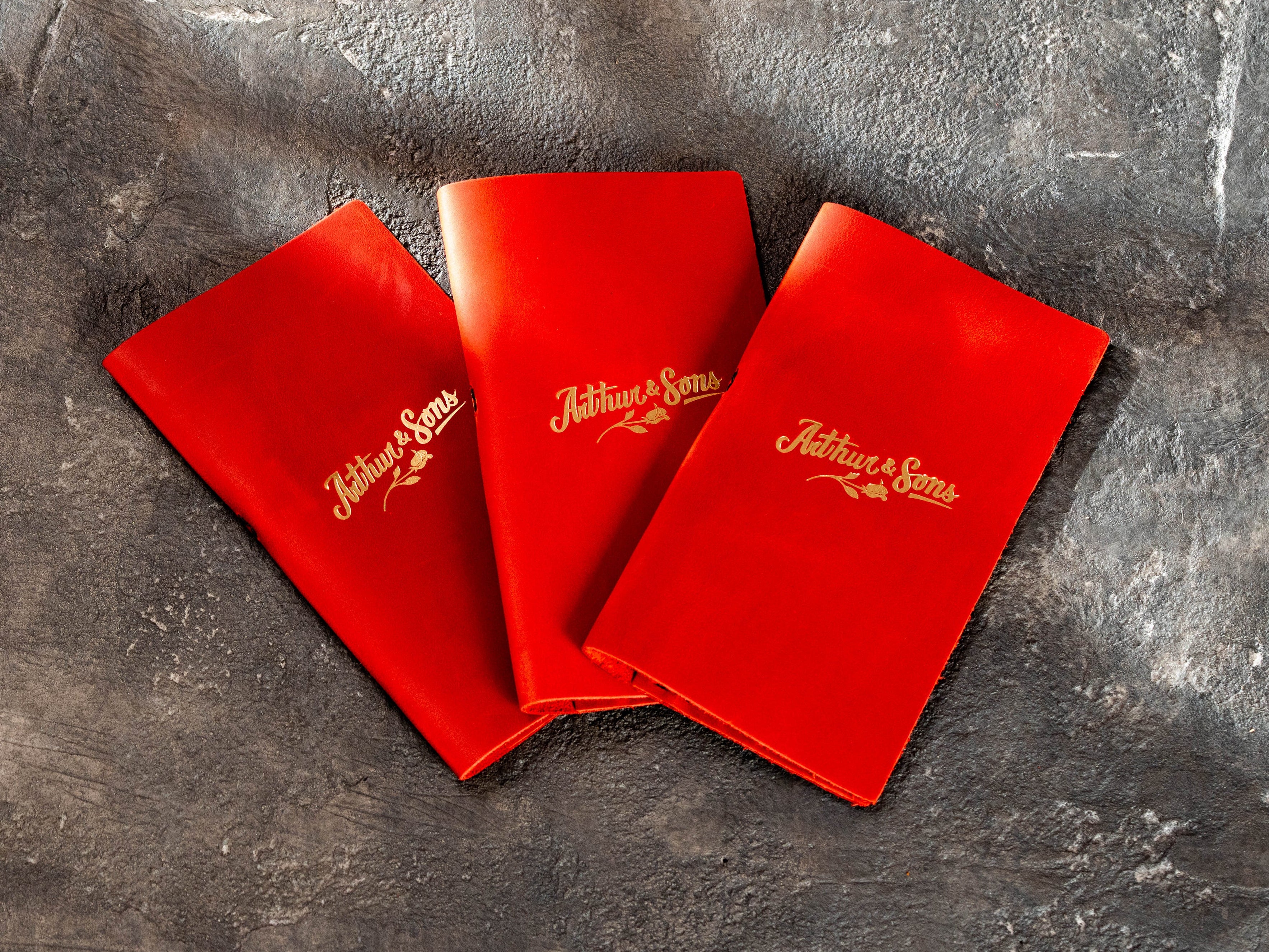 Three custom red leather check presenters with gold logo for restaurant service