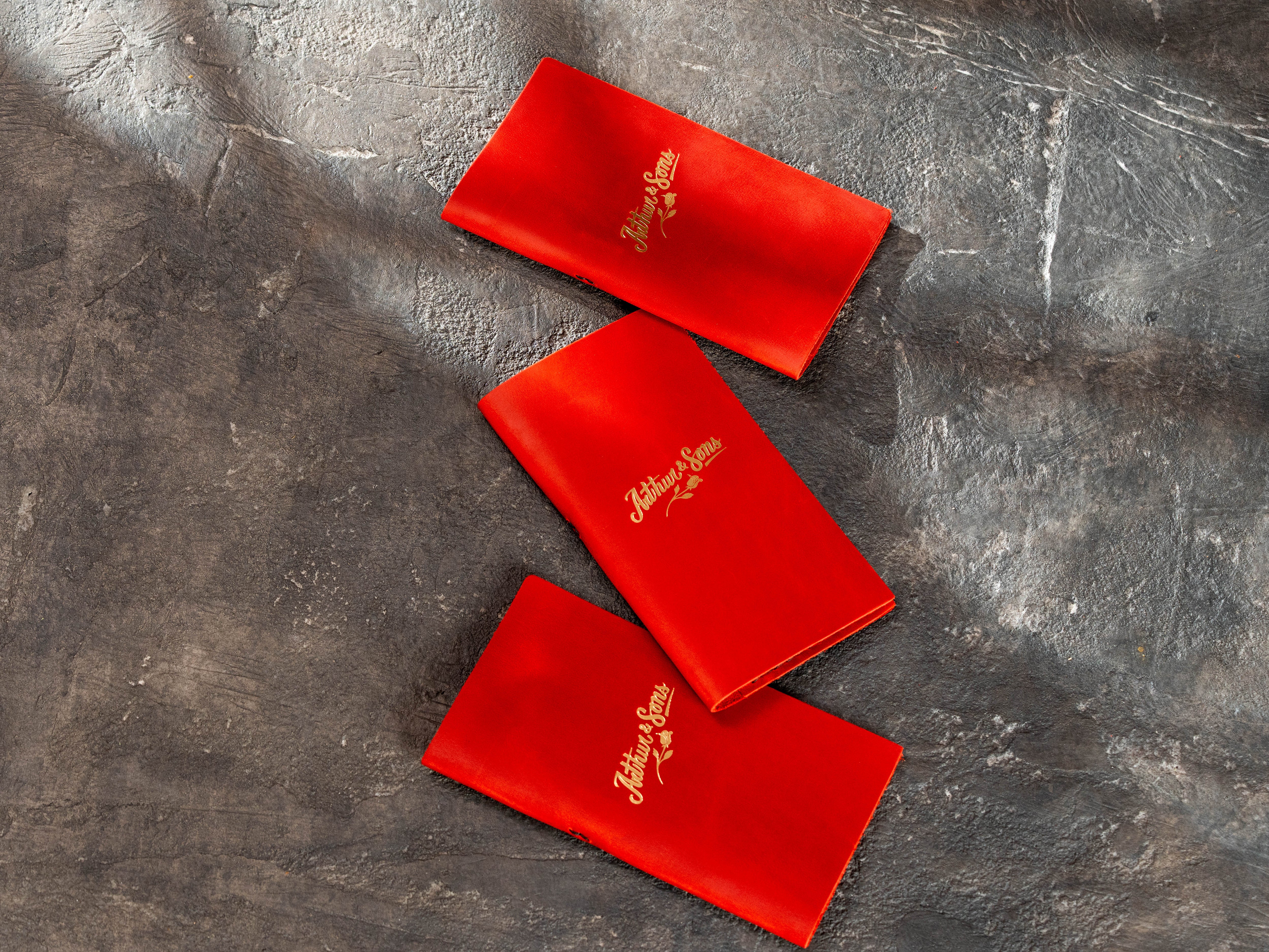 Red leather restaurant check holders arranged with gold custom logo personalization