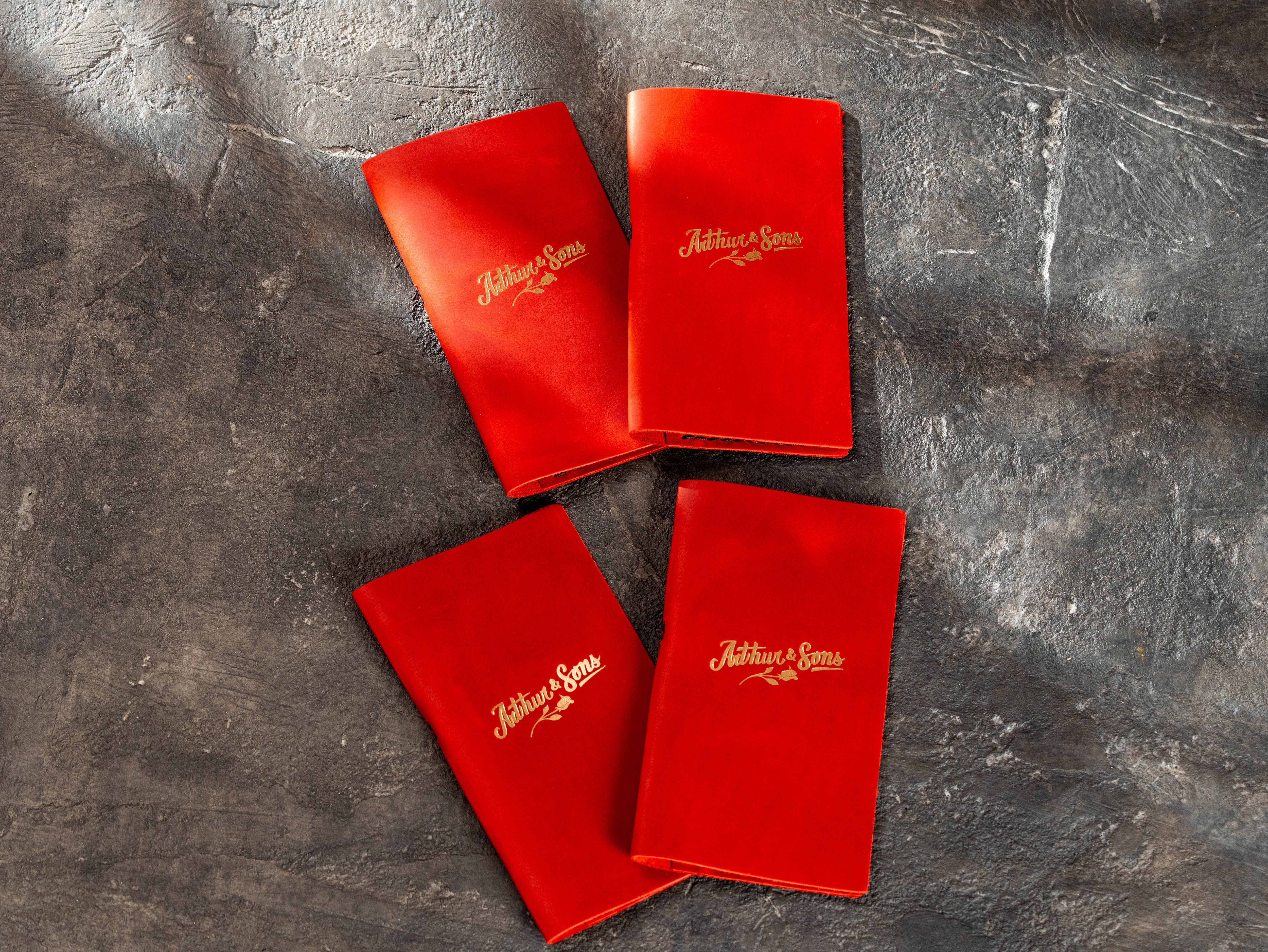 Four red leather bill presenters with gold restaurant logo and handmade construction