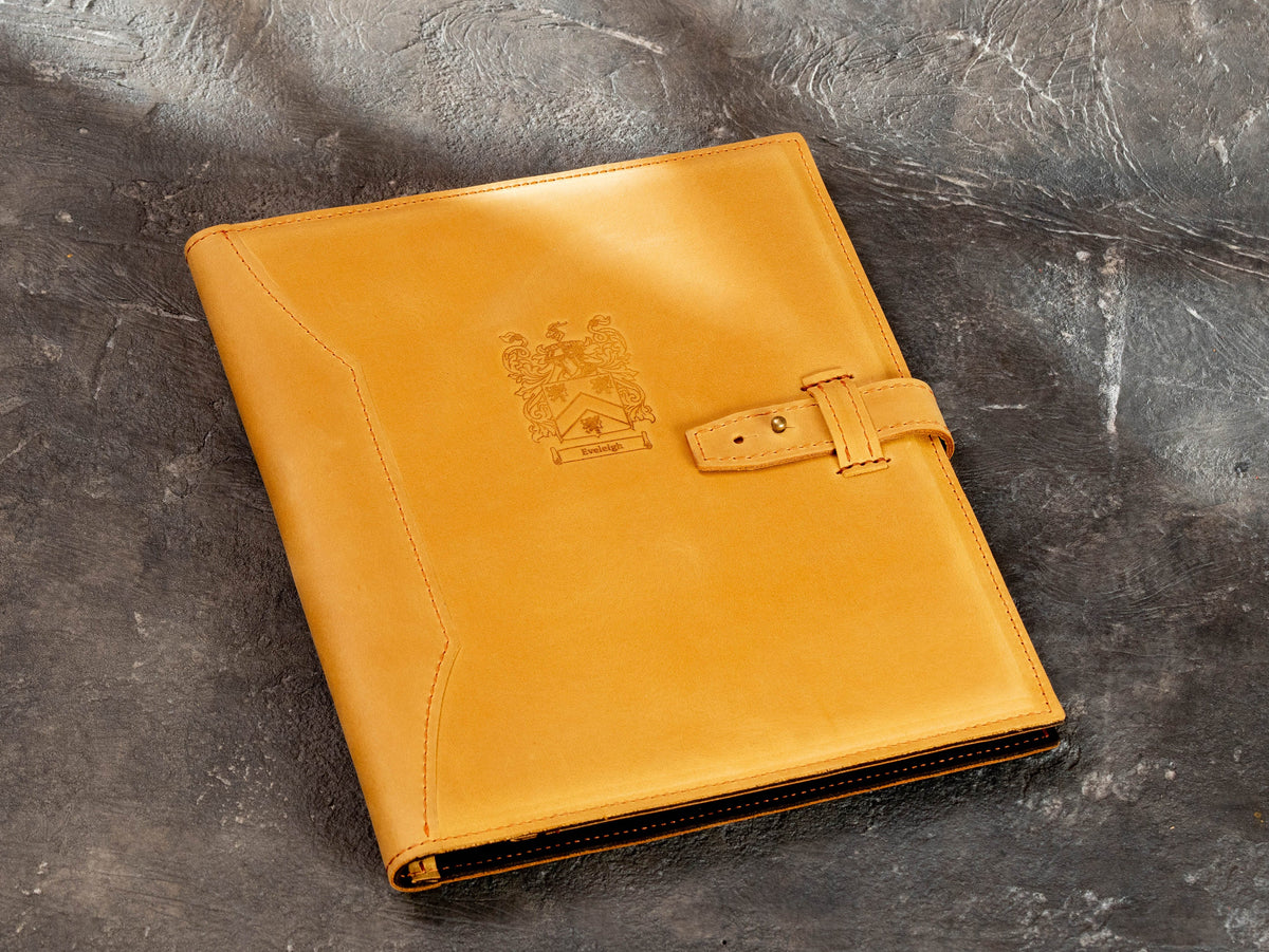 Closed personalized wheat leather portfolio with custom crest and strap closure