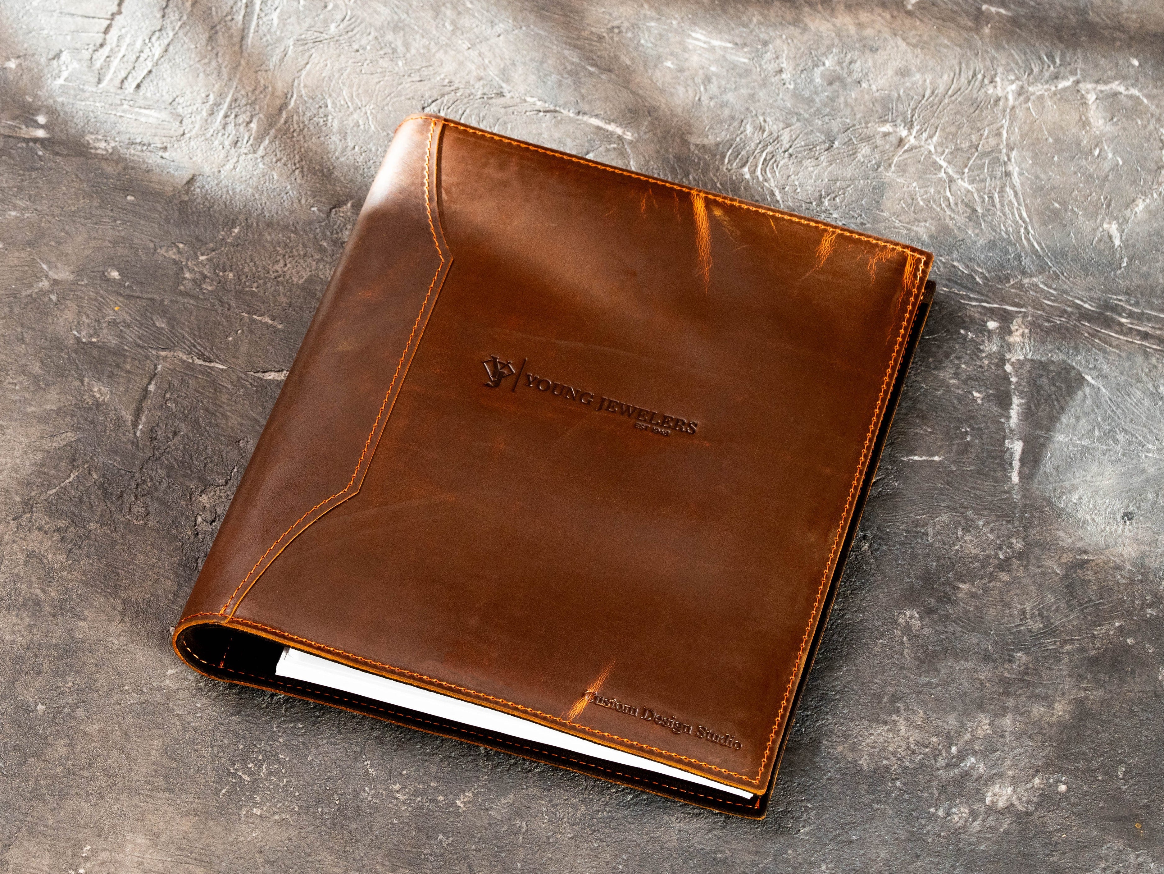 Brown leather corporate binder with embossed company logo and custom text on the front cover.