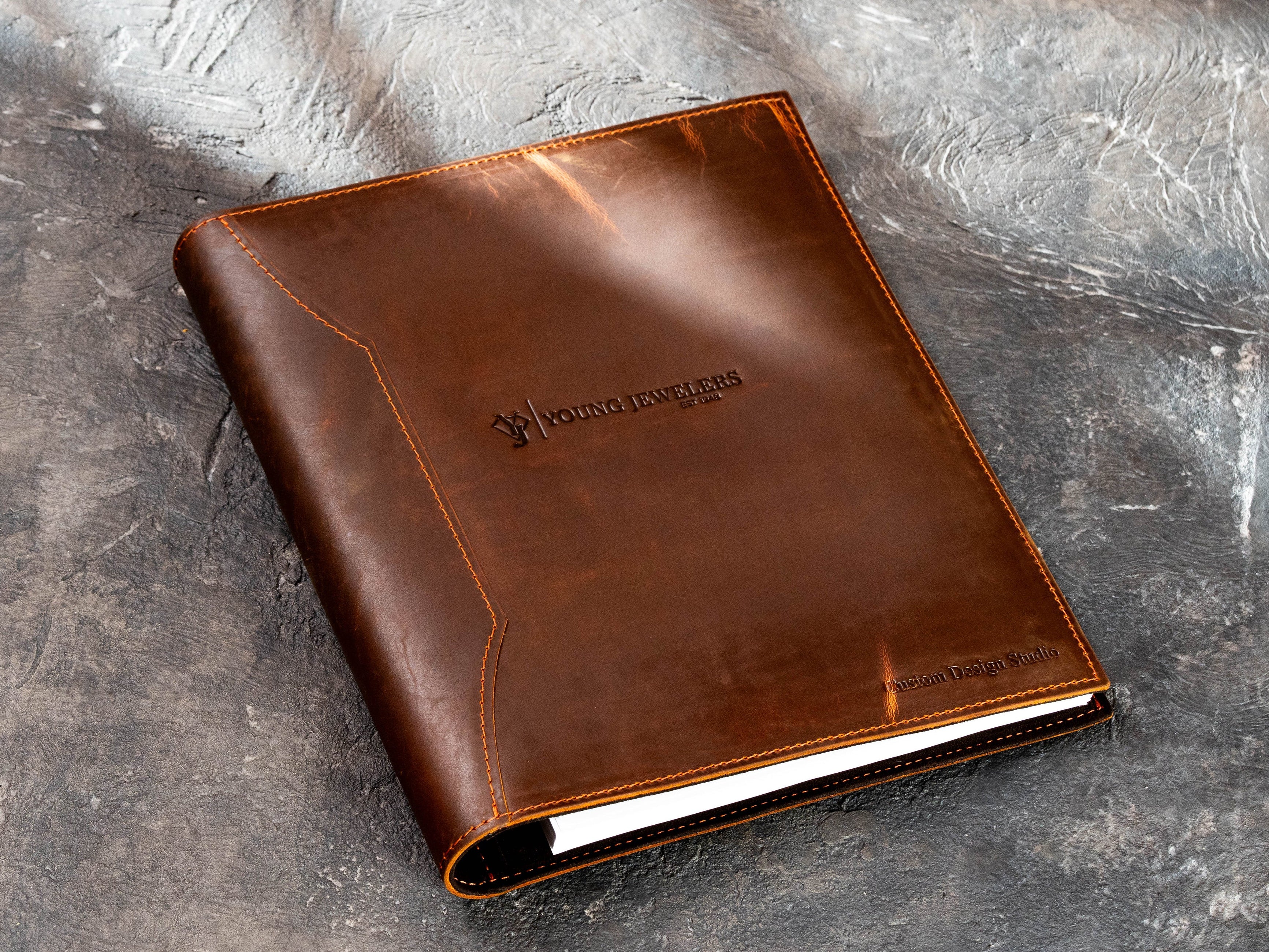 Custom brown leather presentation binder with company logo, stitched cover and professional business design.