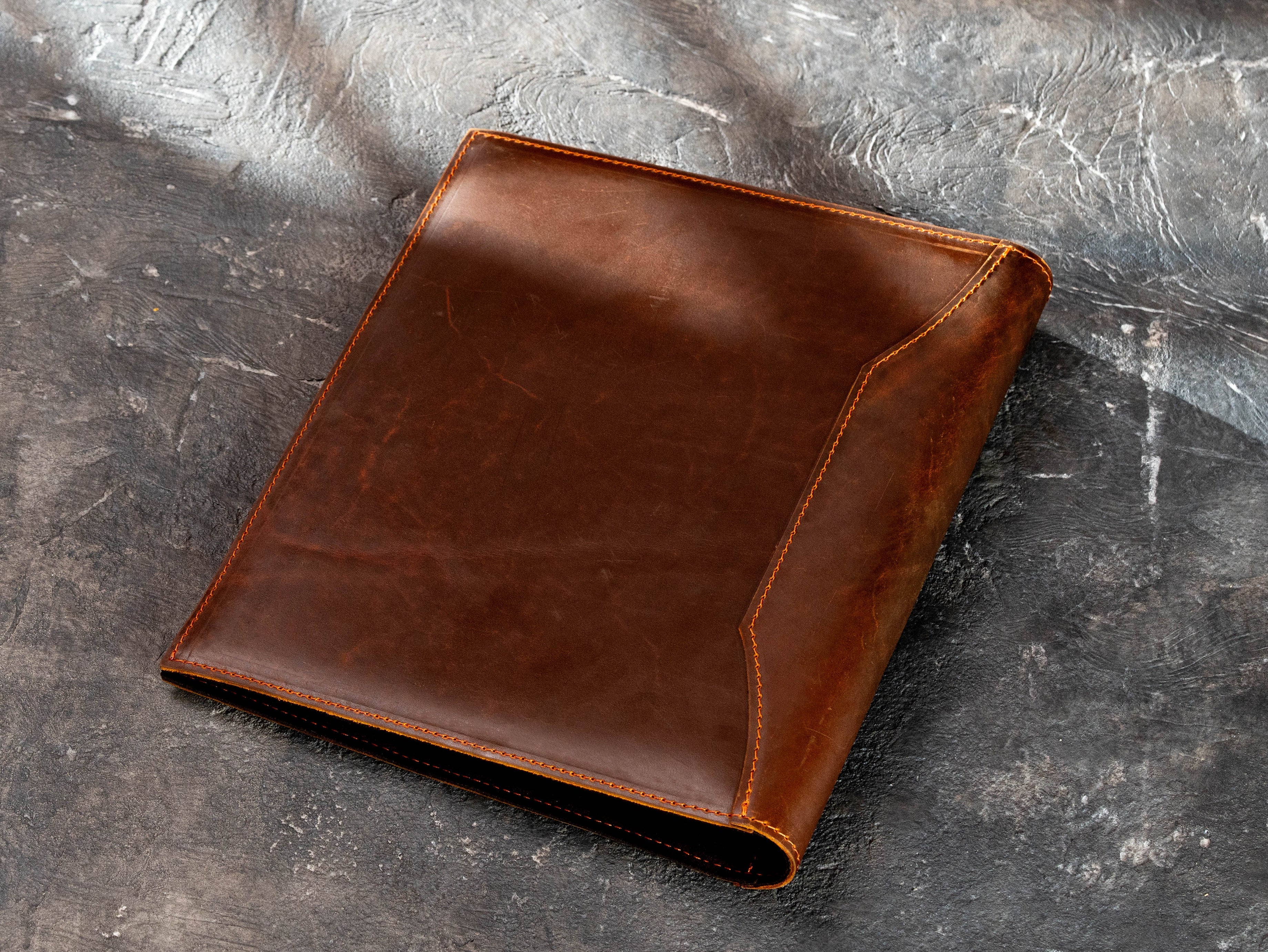 Back view of custom brown leather presentation binder showing natural leather texture and stitched construction.
