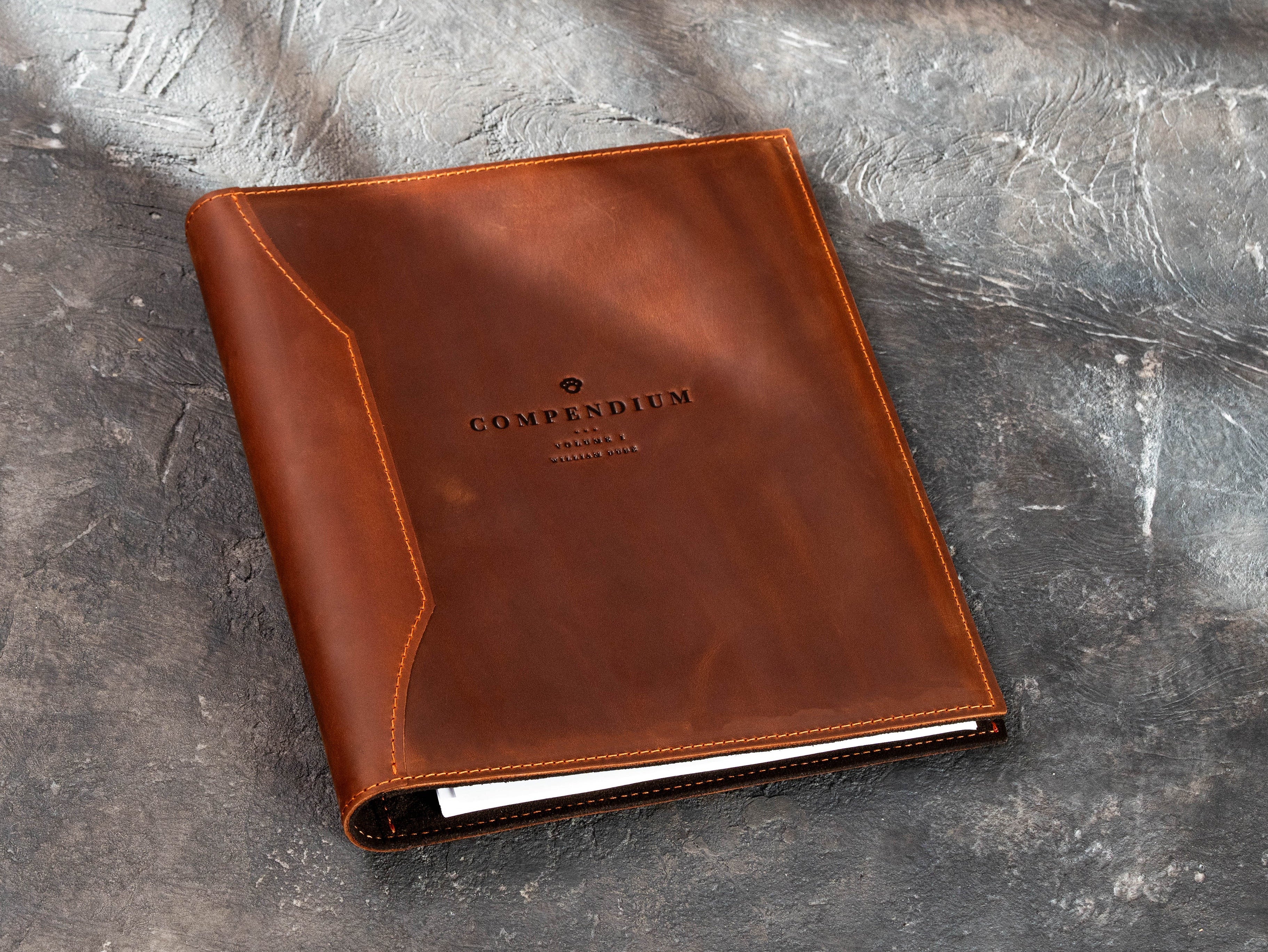 Custom brown leather presentation binder with company logo shown at an angle.