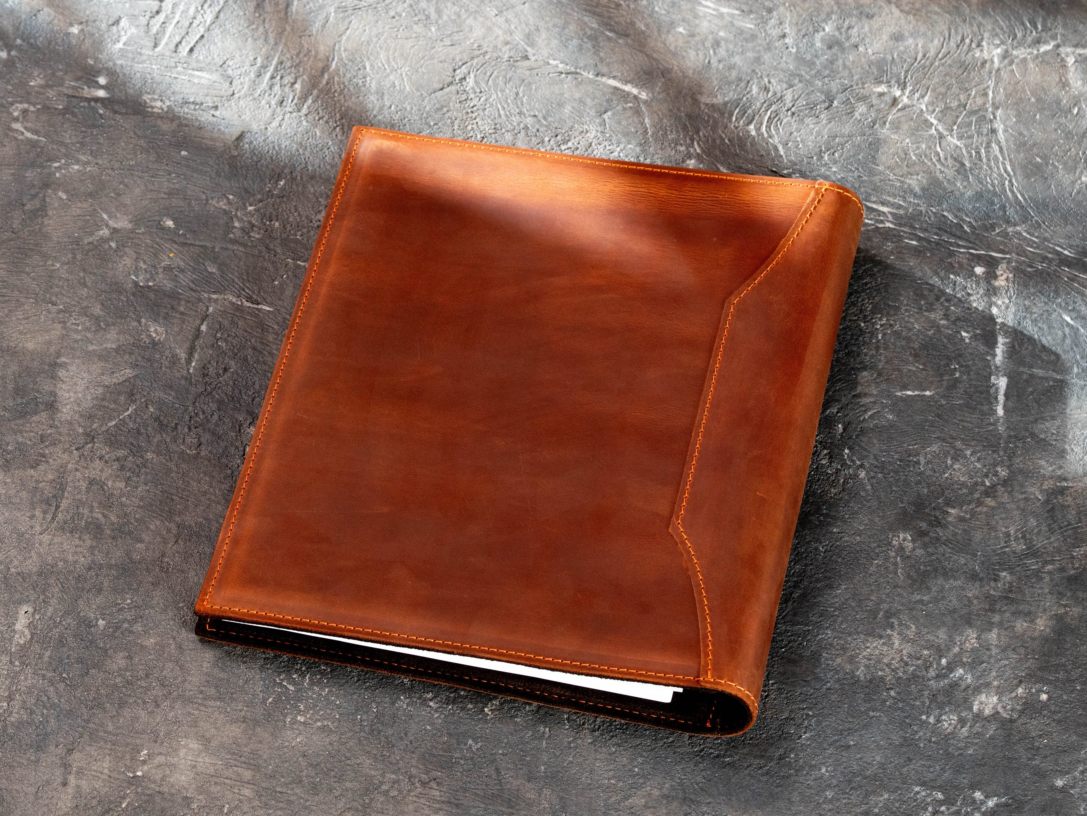 Back view of brown leather corporate binder with stitched construction and natural leather texture.