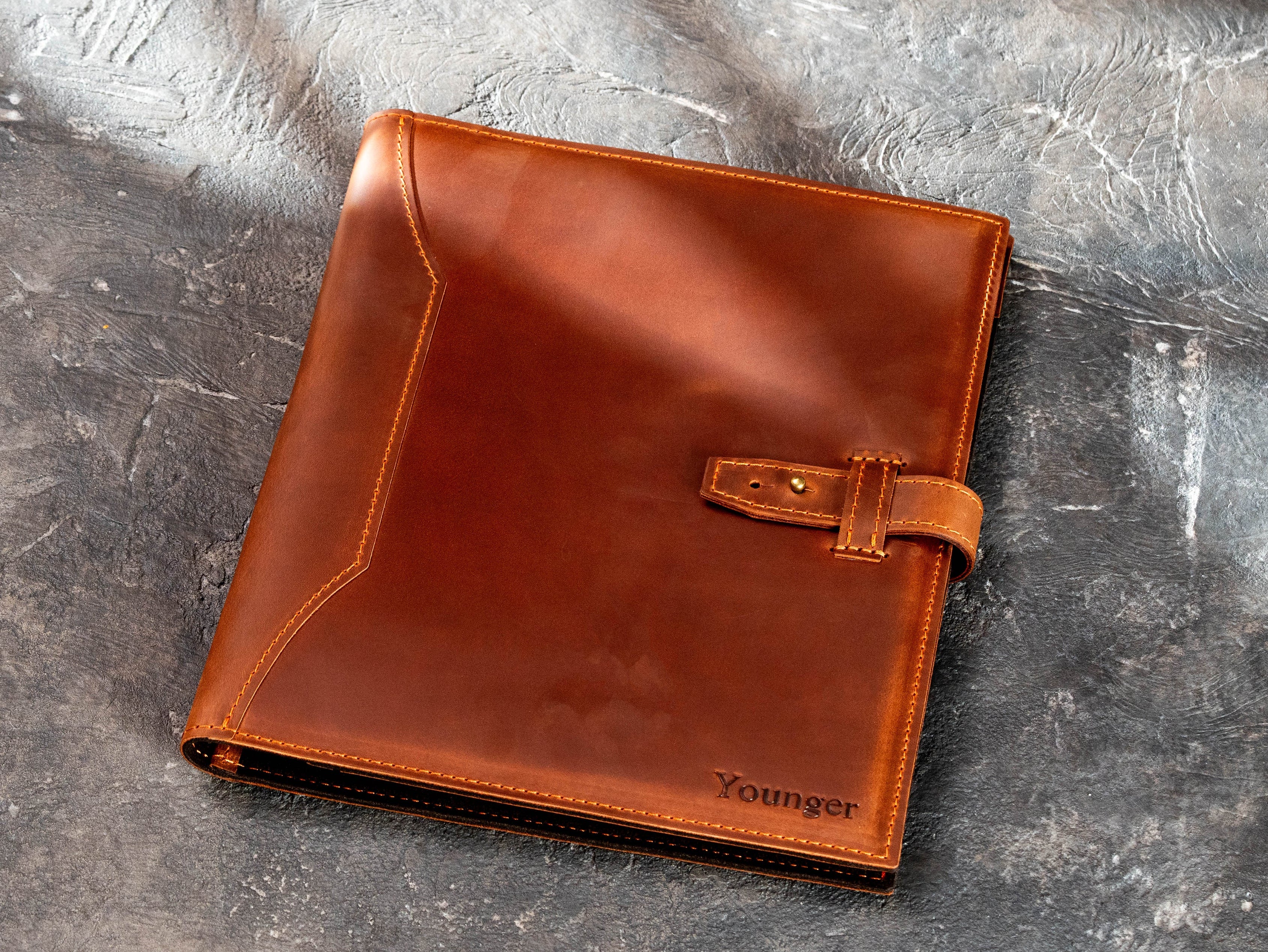 Closed copper leather business portfolio with personalized name and leather strap closure.