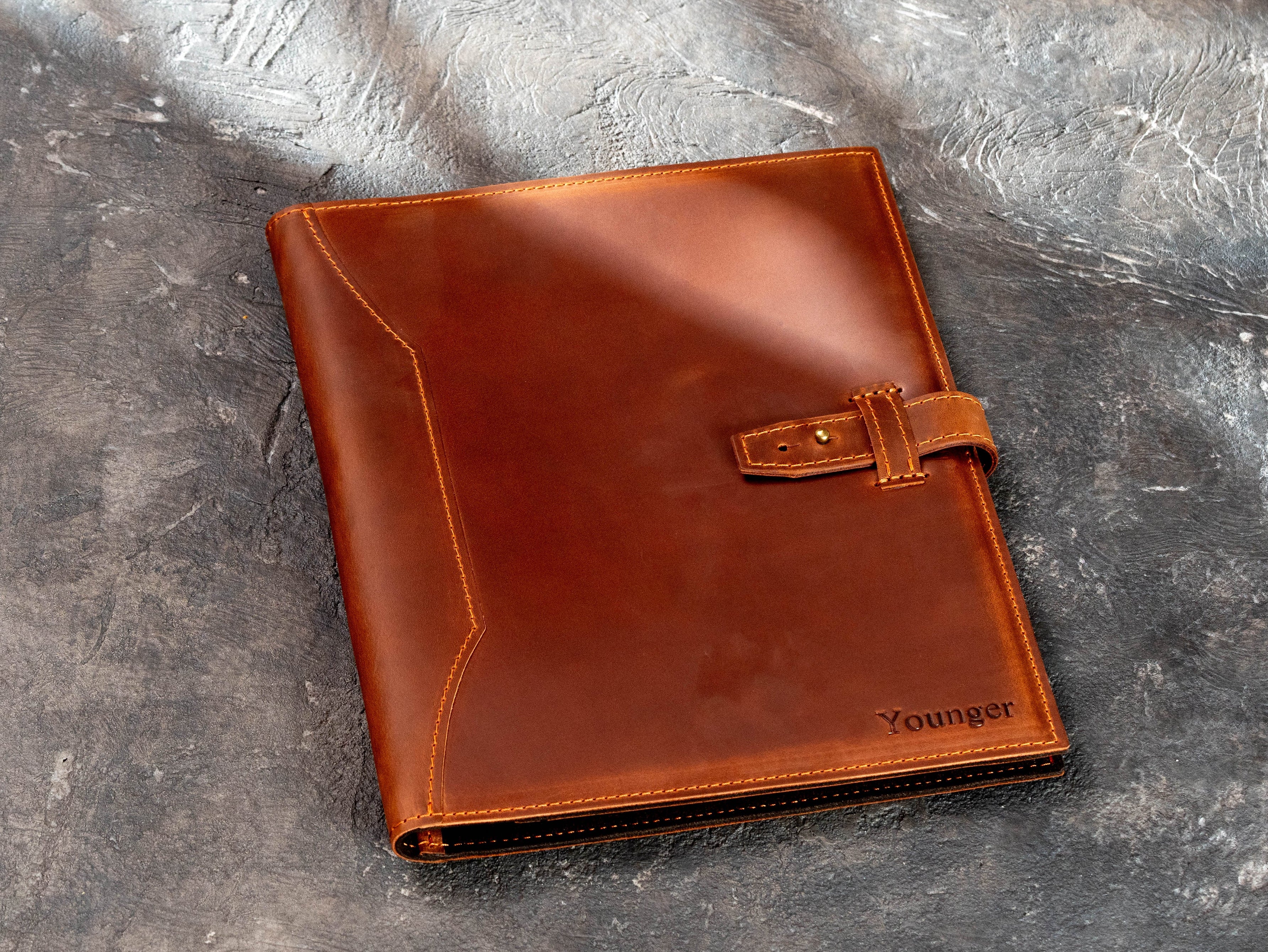 Personalized copper leather executive portfolio showing front cover stitching and name detail.