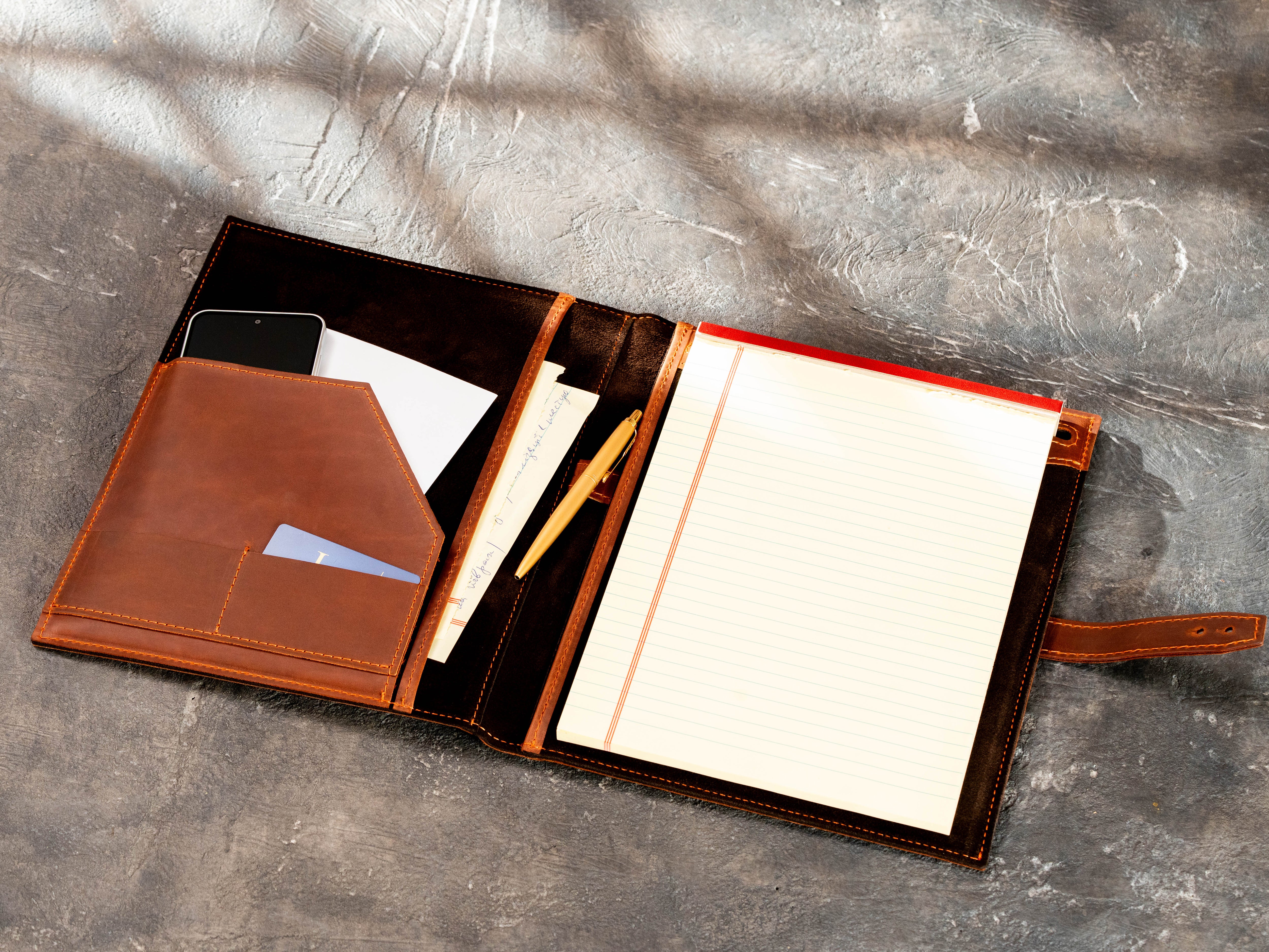 Interior of copper leather business portfolio with legal pad holder and multiple organizer pockets.
