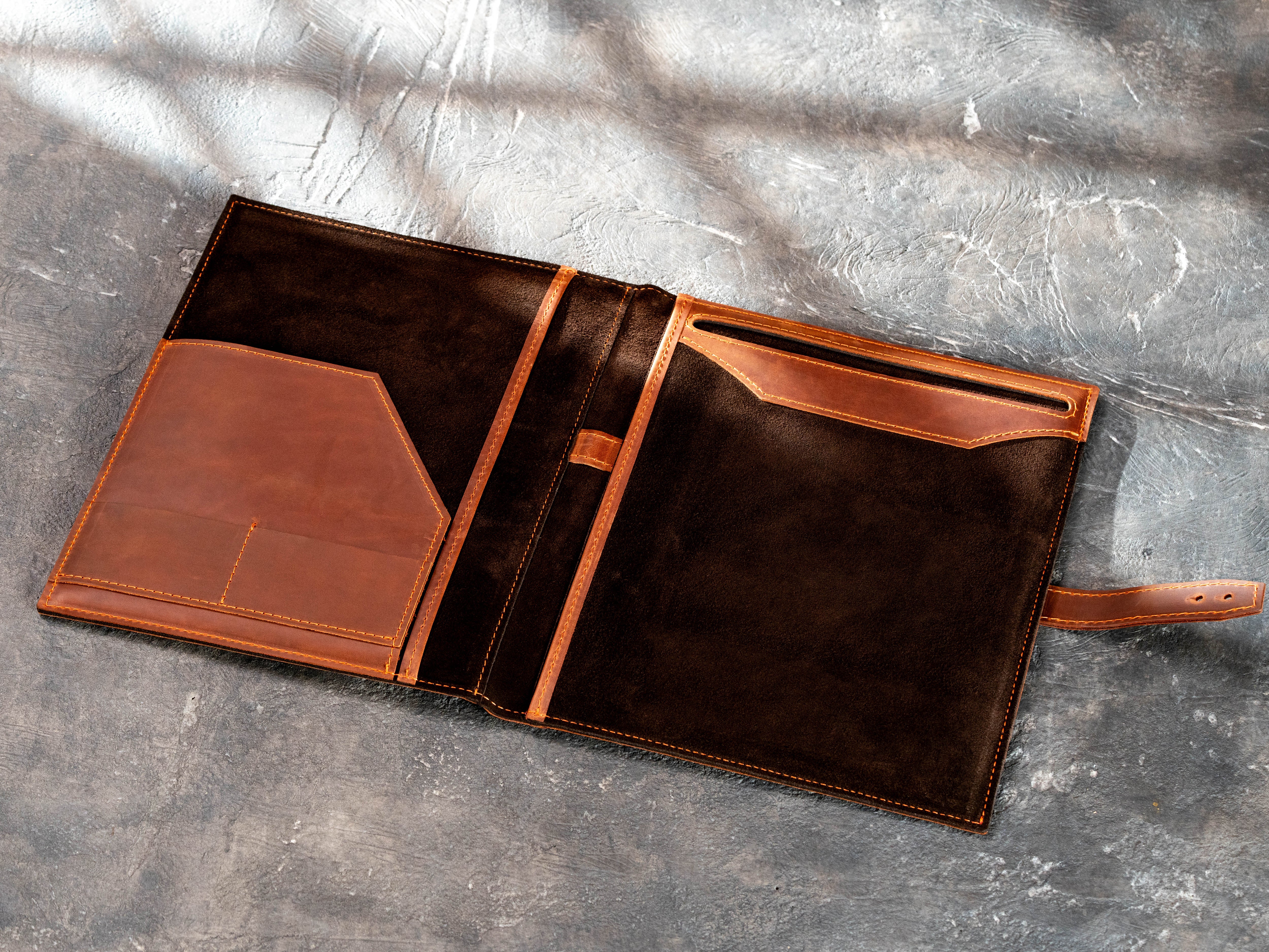 Open leather legal pad portfolio with tablet pocket, business card slots, documents and pen.