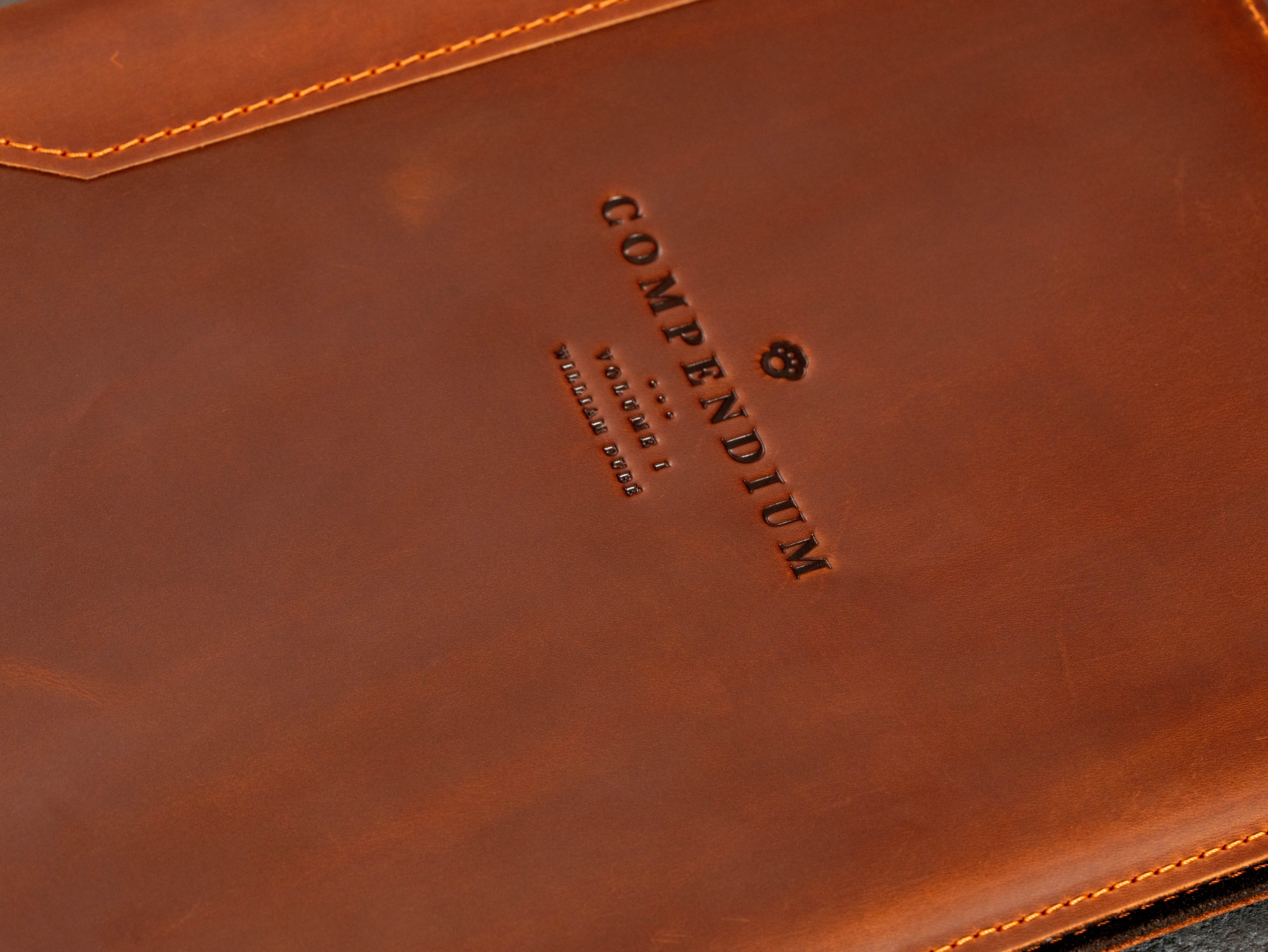 Close-up of Compendium logo embossed on custom brown leather corporate binder.