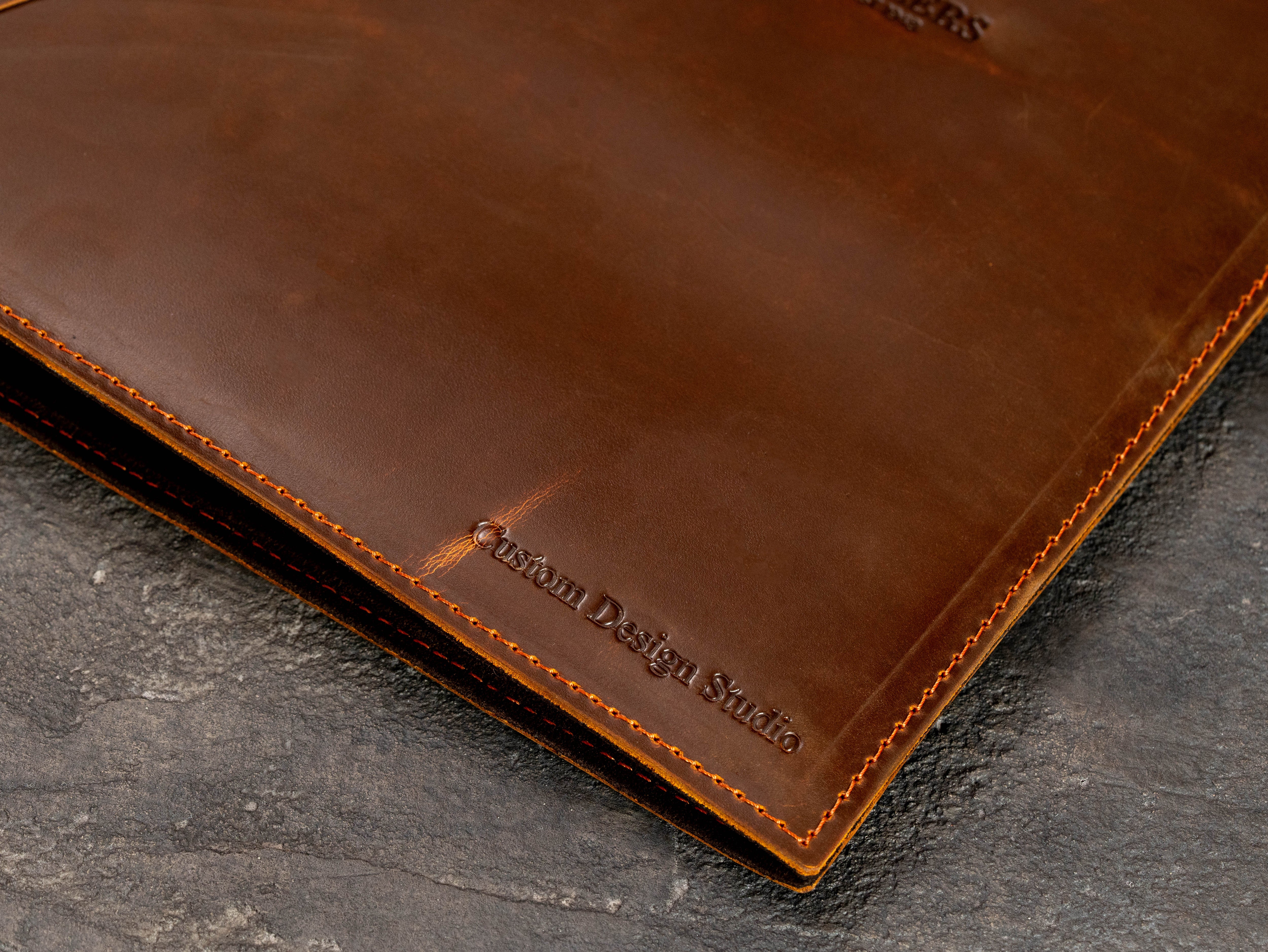 Close-up of custom text embossing on the lower corner of brown leather corporate binder.