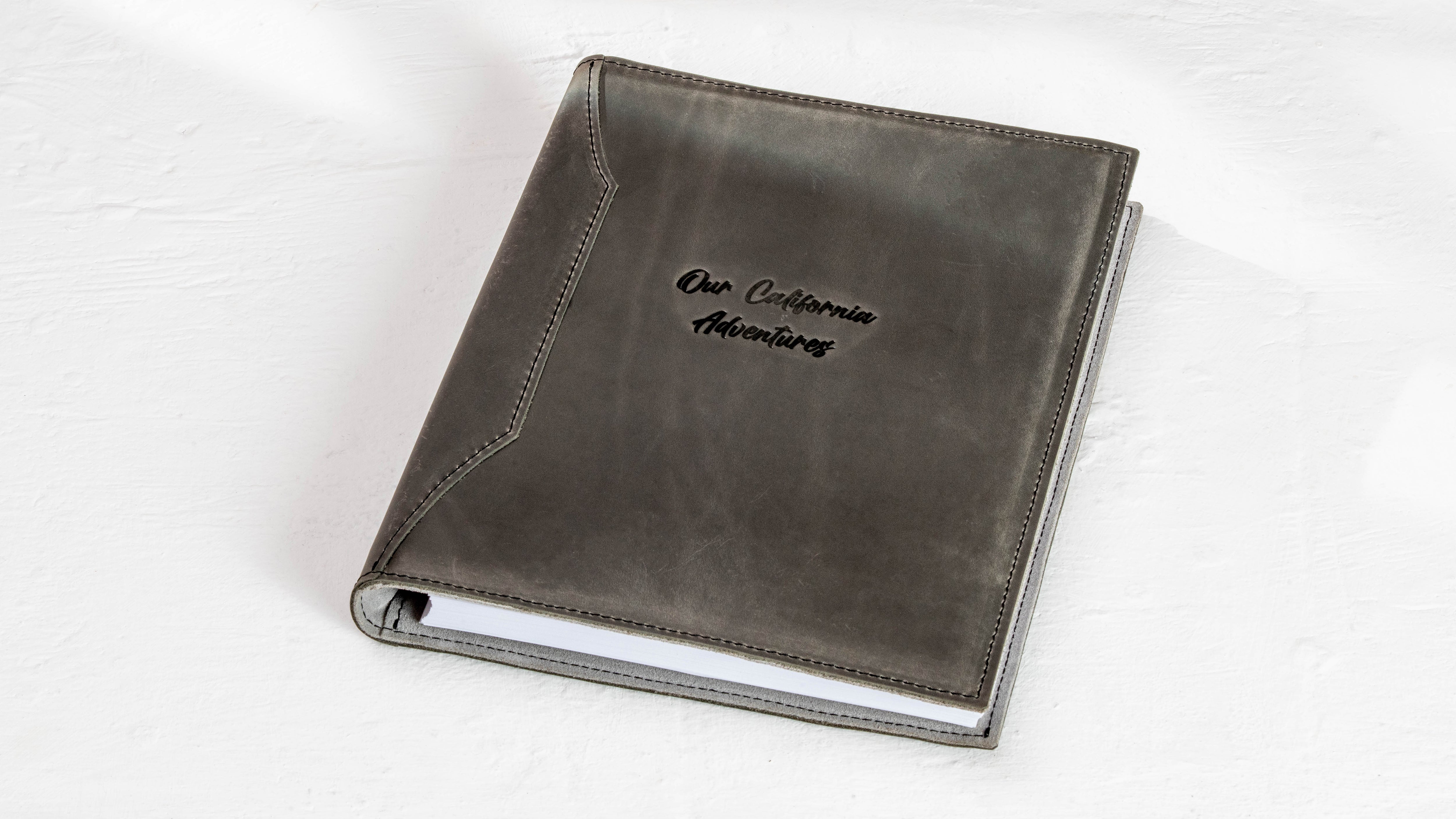 Charcoal gray leather vacation keepsake binder showing its light suede interior and 25 mm rings.