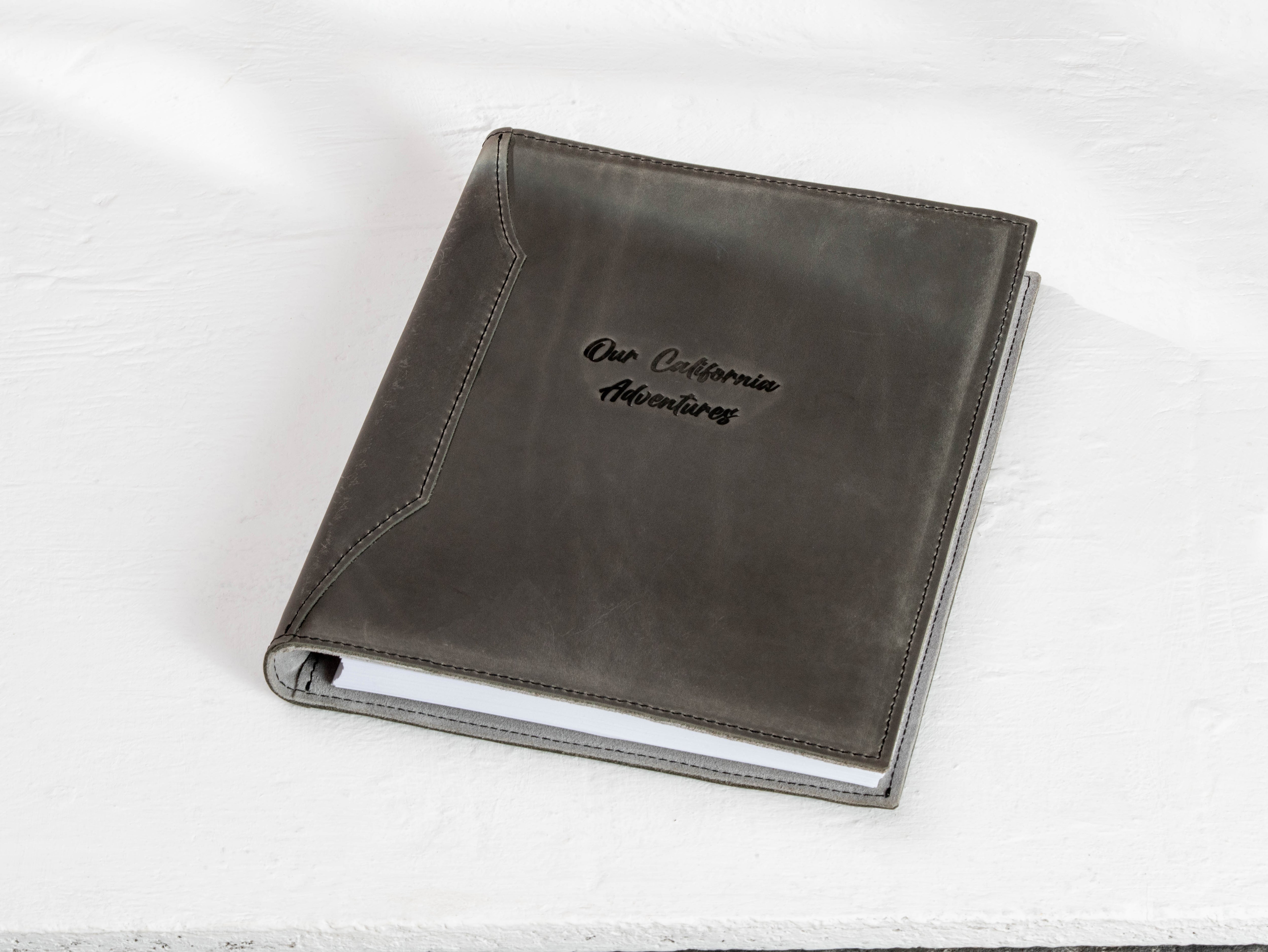 Personalized charcoal gray leather travel memory binder with “Our California Adventures” title on a light studio background.