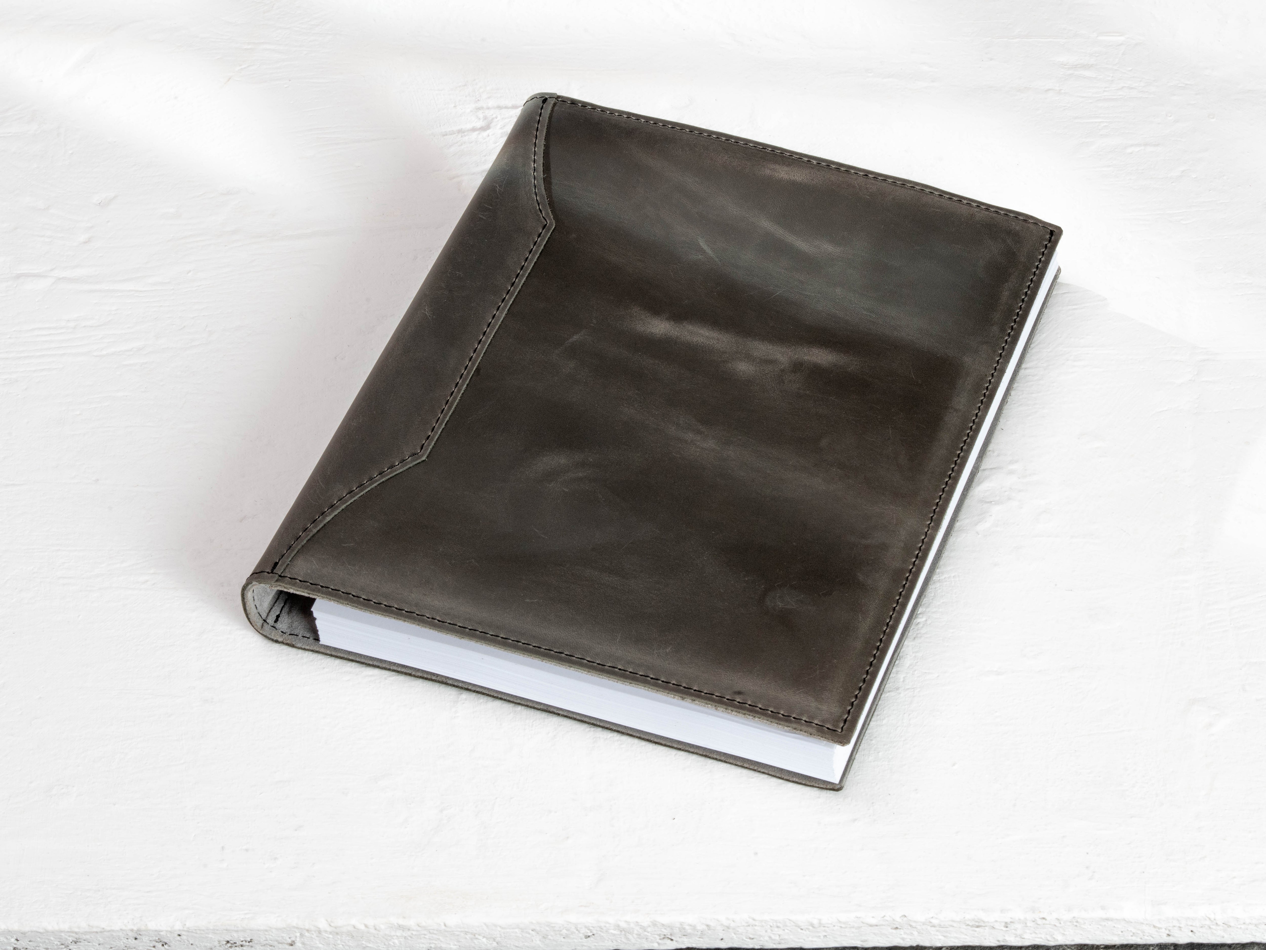 Back view of charcoal gray leather travel archive binder showing stitched construction.
