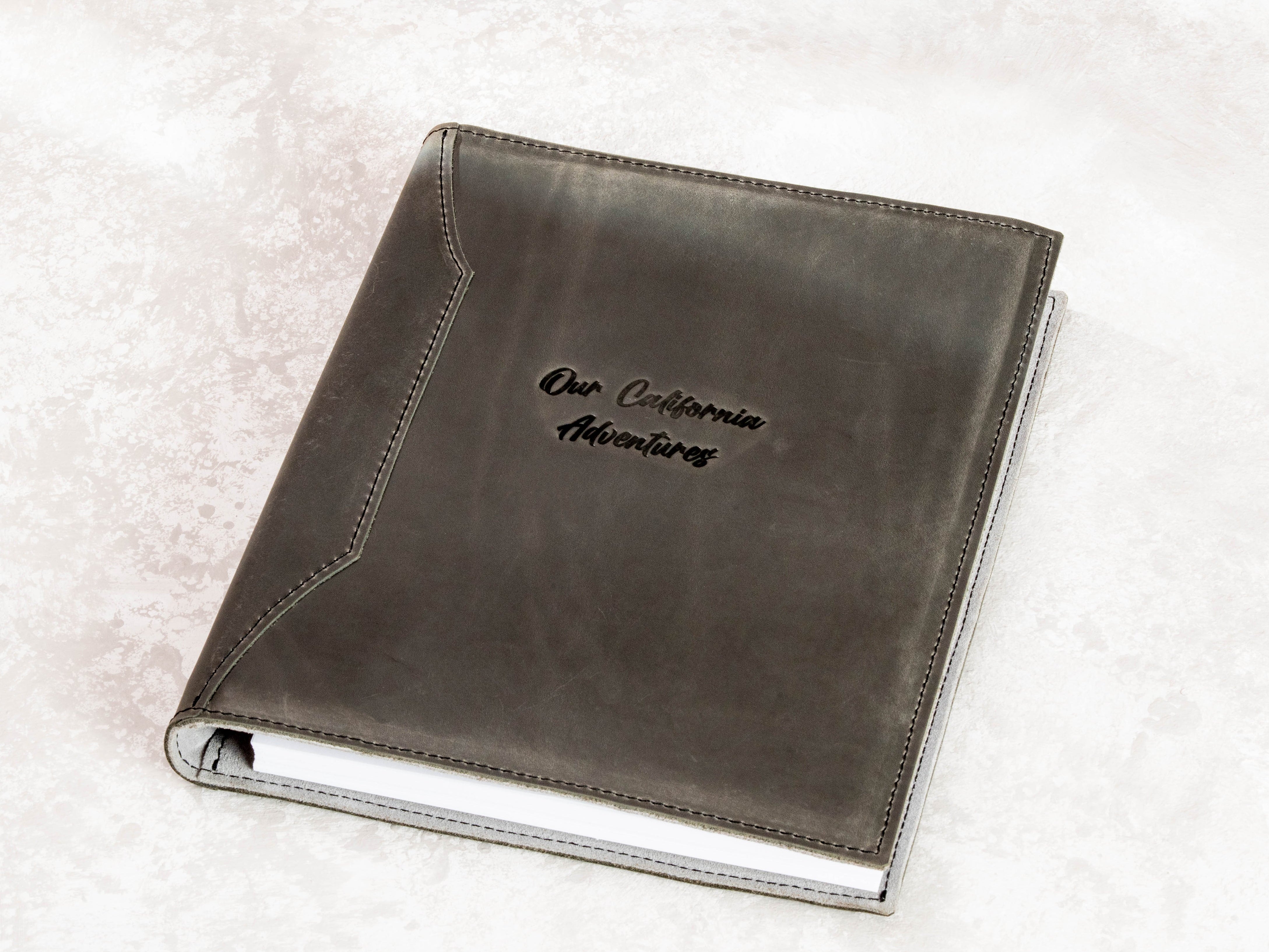Charcoal gray leather travel memory binder with personalized “Our California Adventures” embossing and custom metal die.