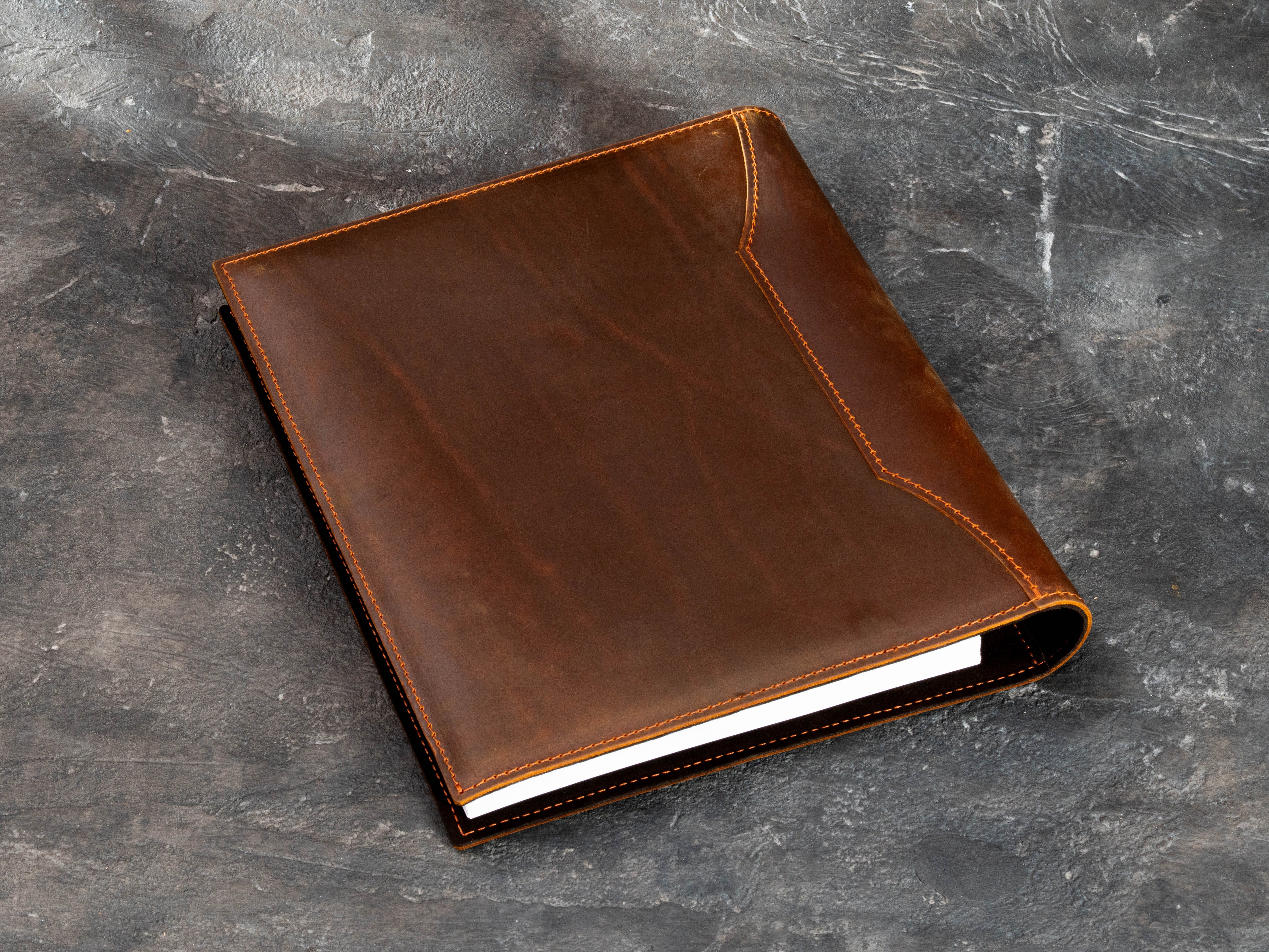 Back view of the warm brown leather 3-ring musician binder showing stitched construction and smooth leather surface.