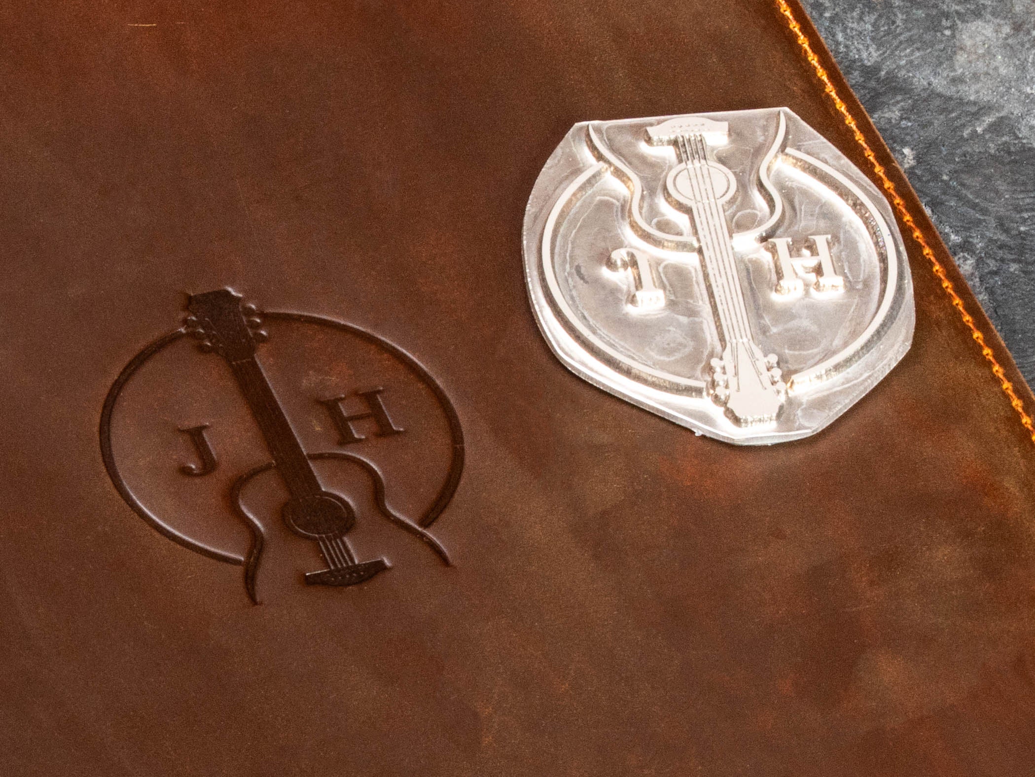 Close-up of custom guitar embossing beside the client’s embossing die used to create the personalized design.