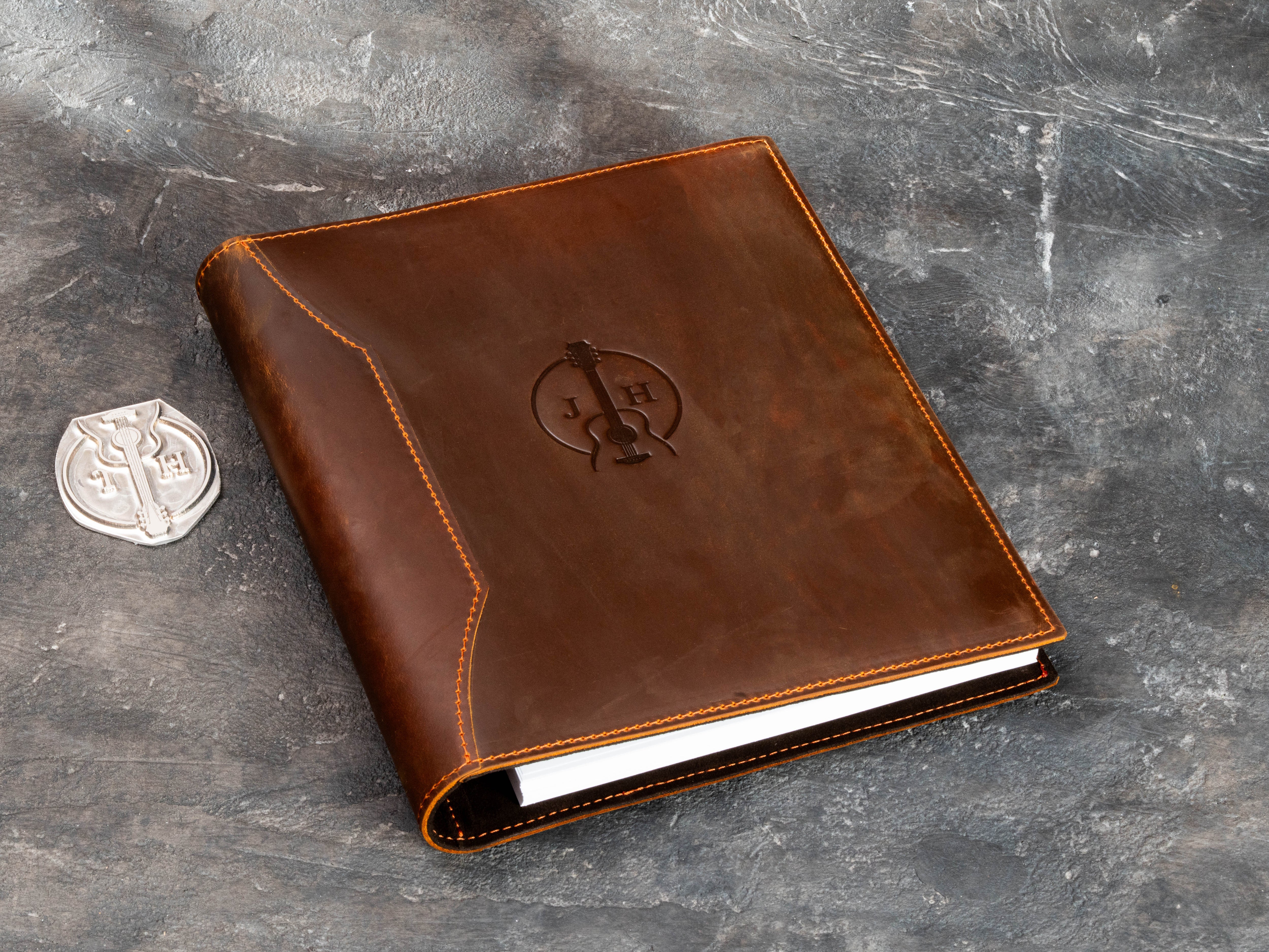 Brown leather musician binder shown with custom guitar embossing die, highlighting the personalized production process.