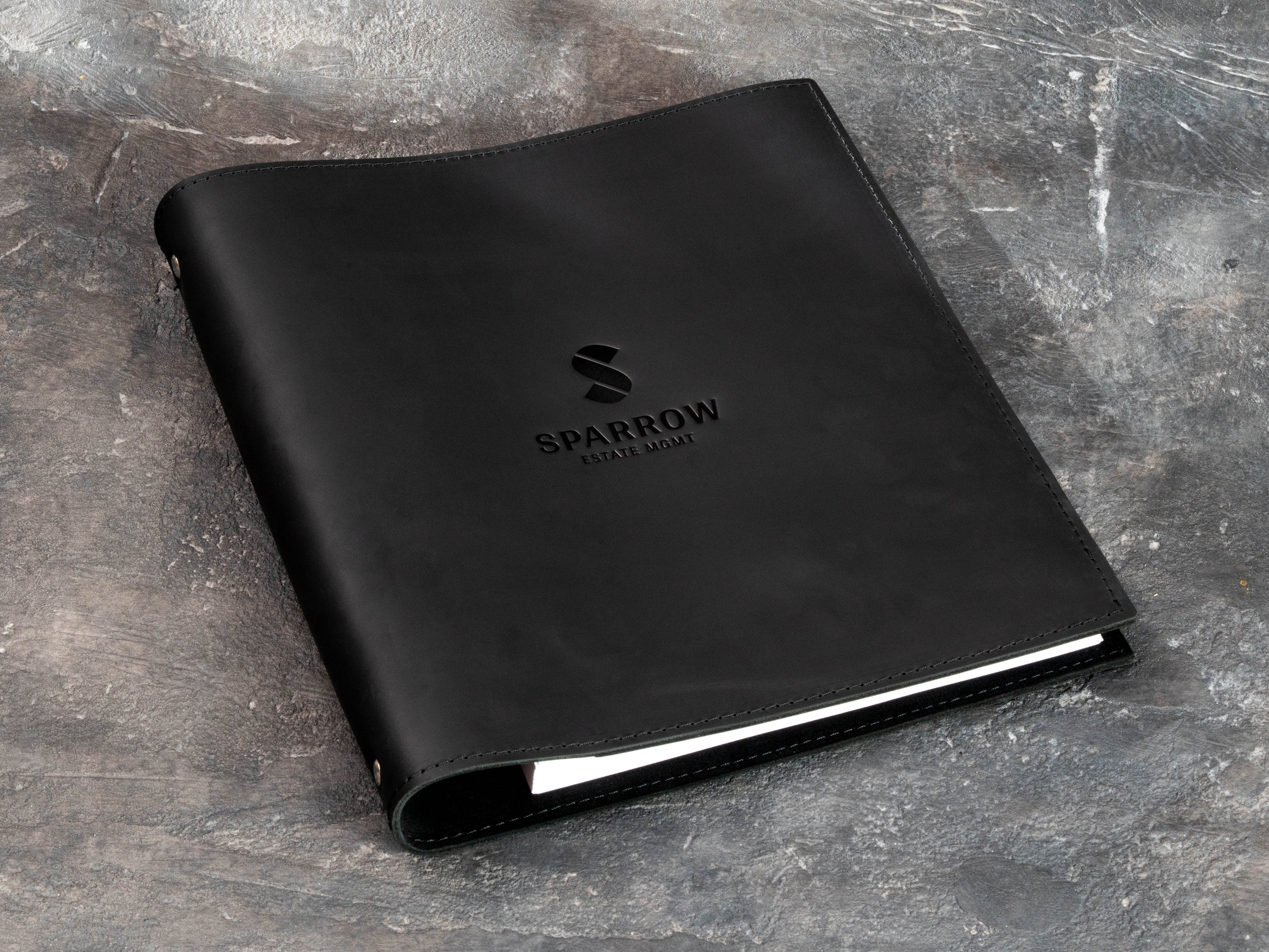 Soft black leather portfolio folder with custom logo, angled view showing clean minimalist design
