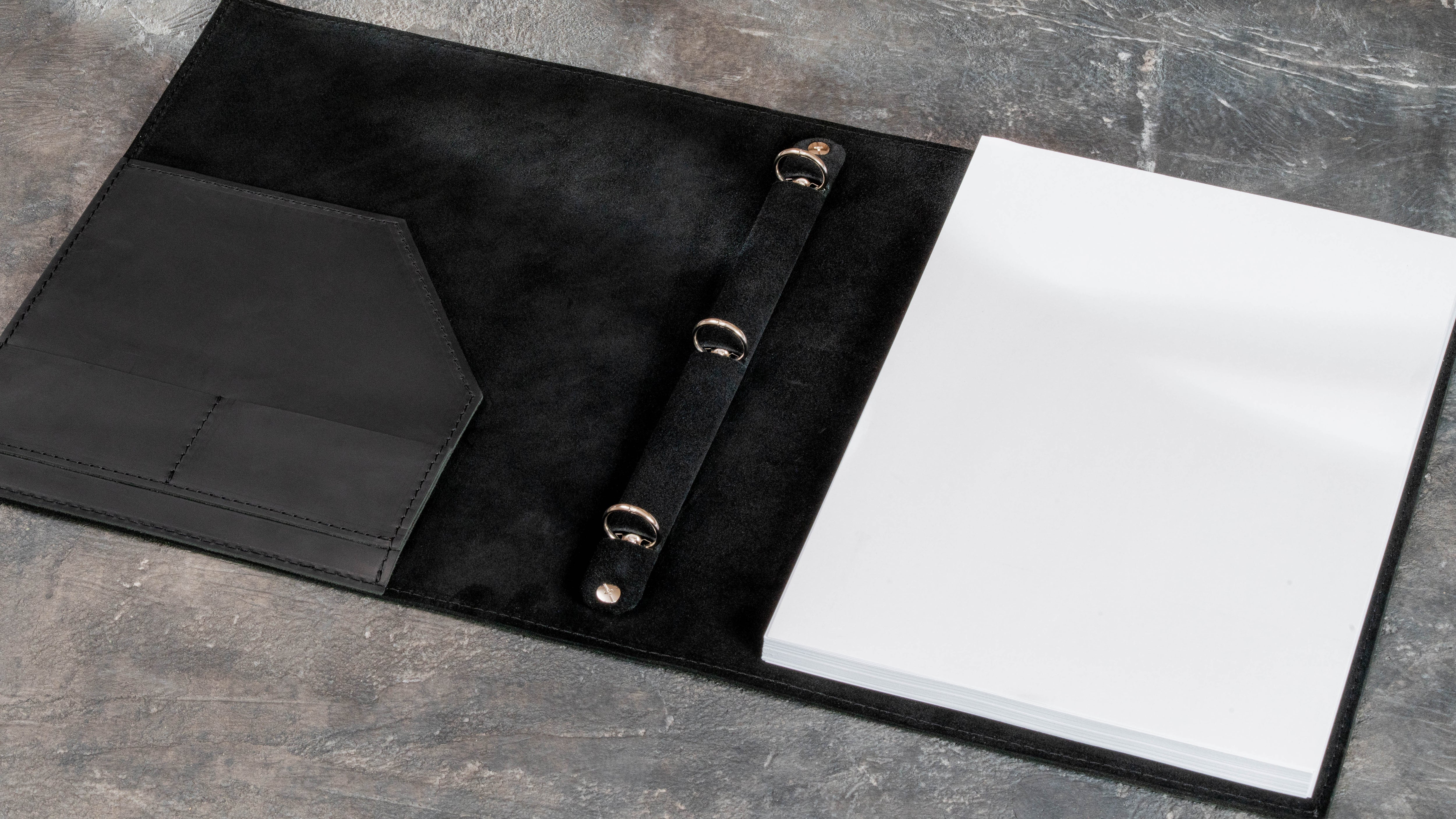 Open black leather portfolio binder with inner pocket, 3-ring mechanism, and A4 document insert