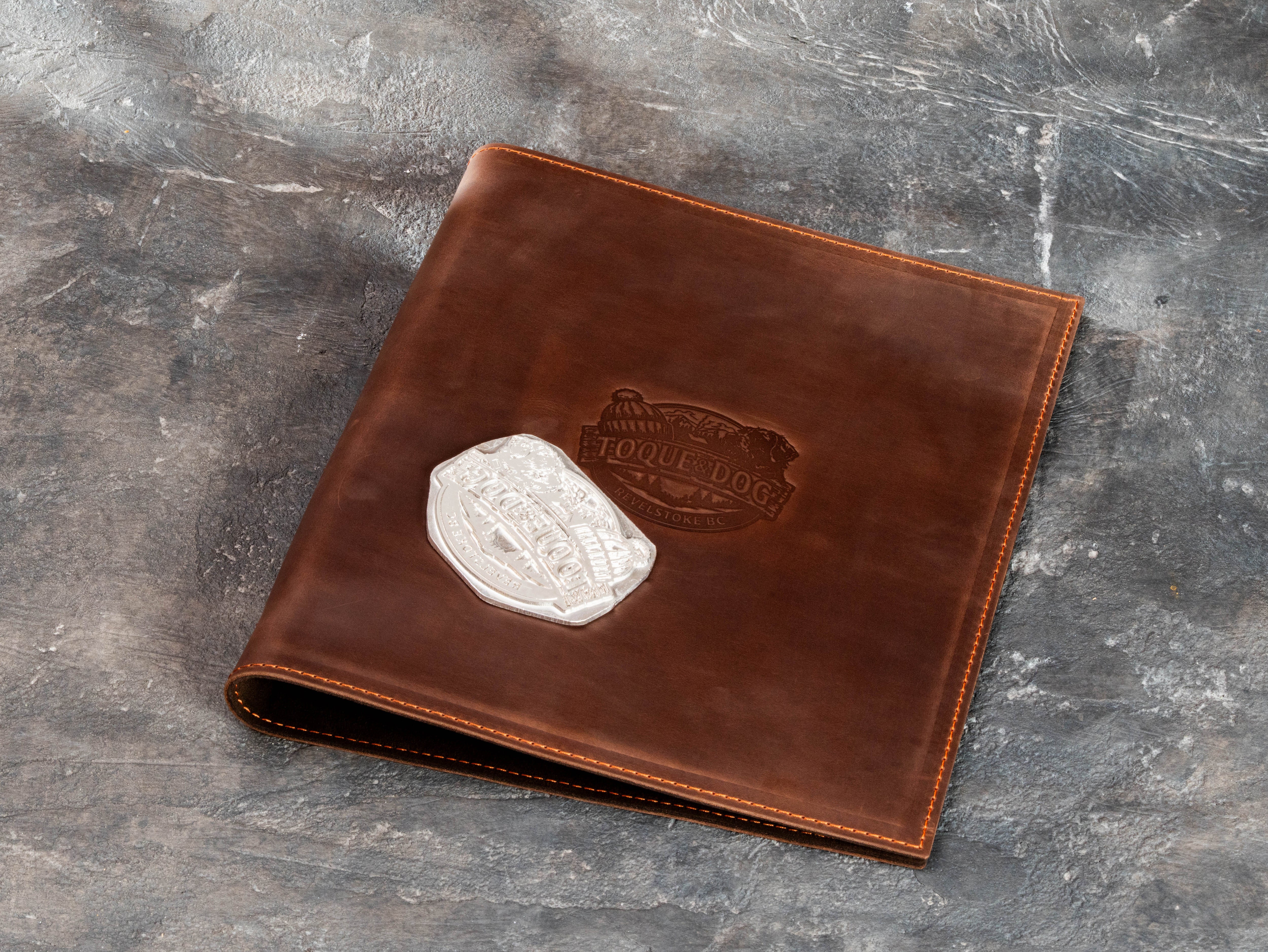 Custom brown leather travel business binder with large embossed client logo and stitched edges
