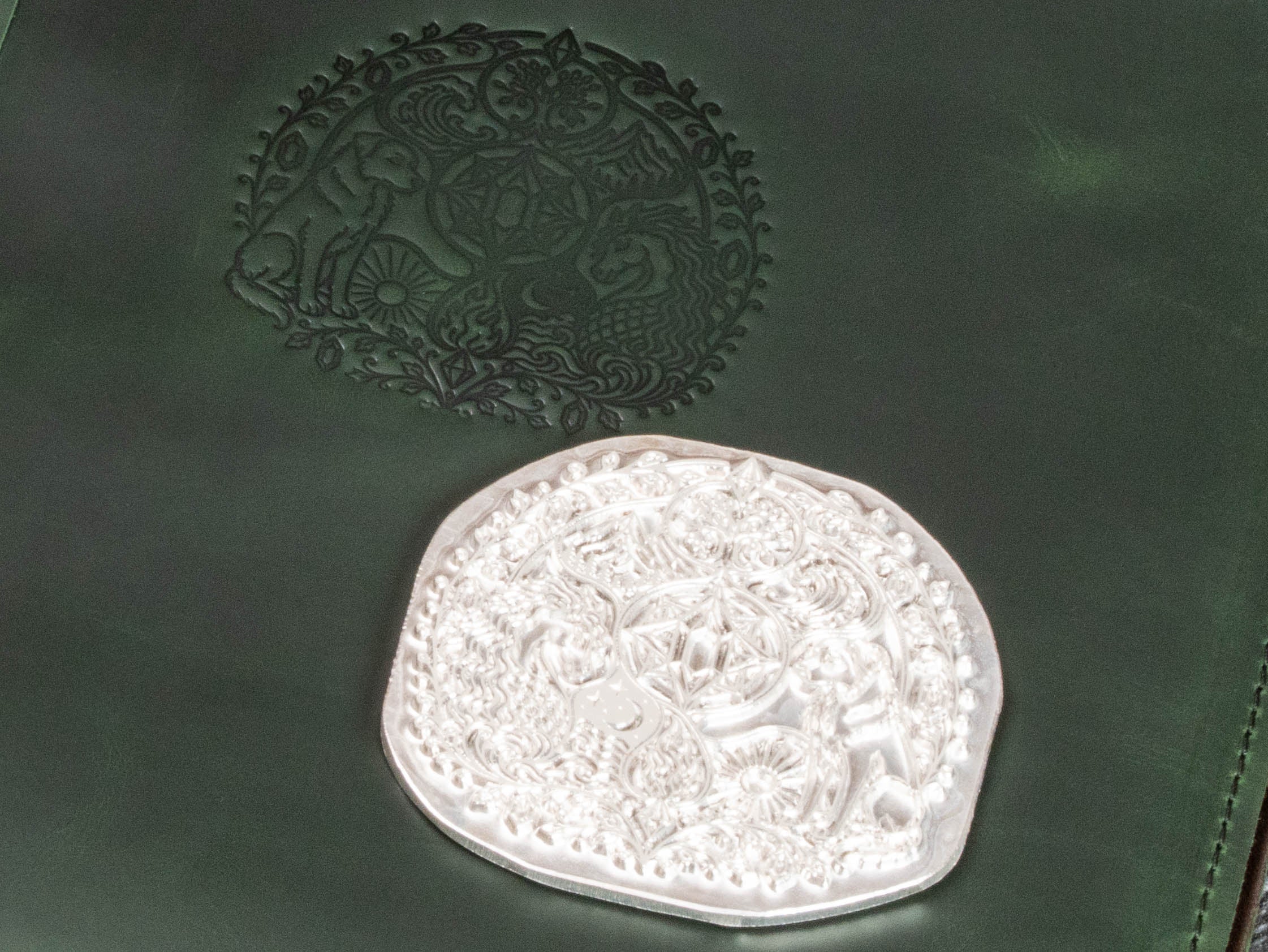 Close-up of custom embossing die and detailed storybook artwork pressed into green leather