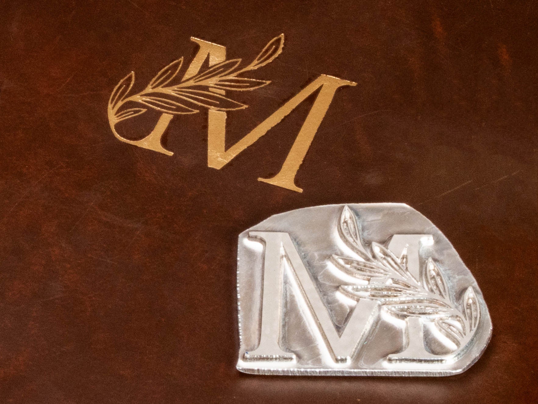 Close-up of gold monogram personalization on chestnut brown leather binder