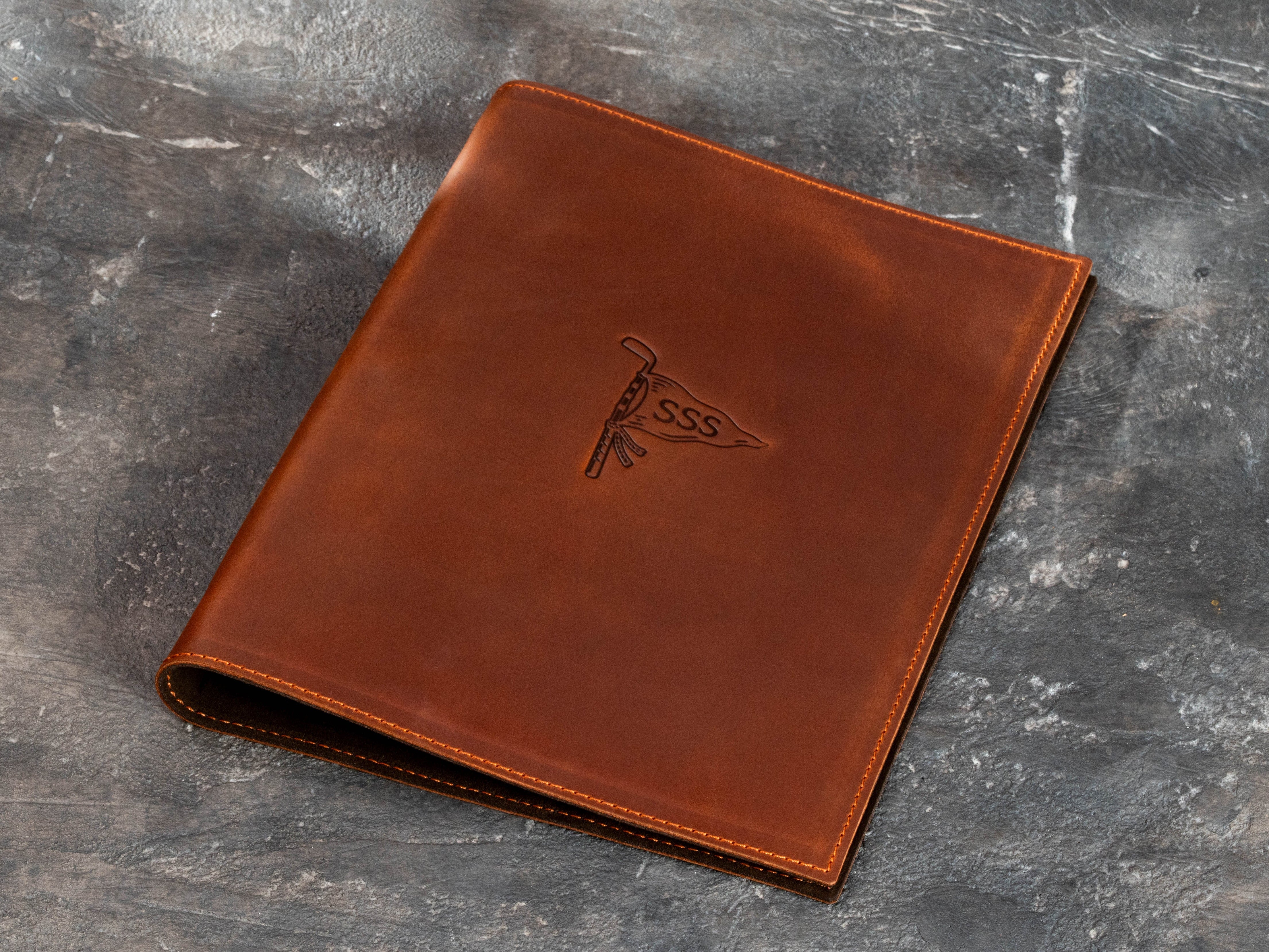 Chestnut brown leather golf binder with custom embossed golf flag design on the front cover
