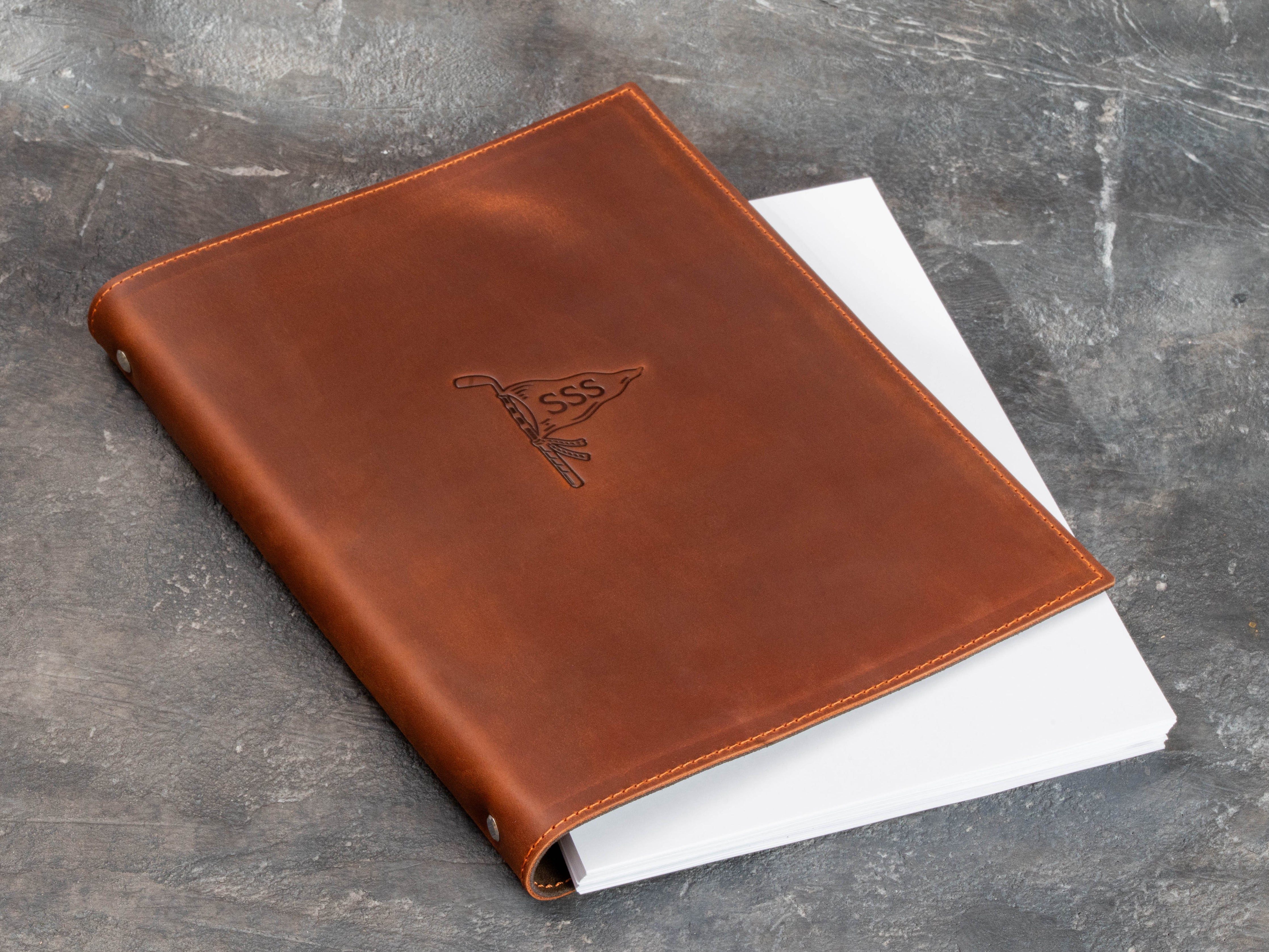 Leather golf scorecard binder with custom embossed design and pages placed inside the cover