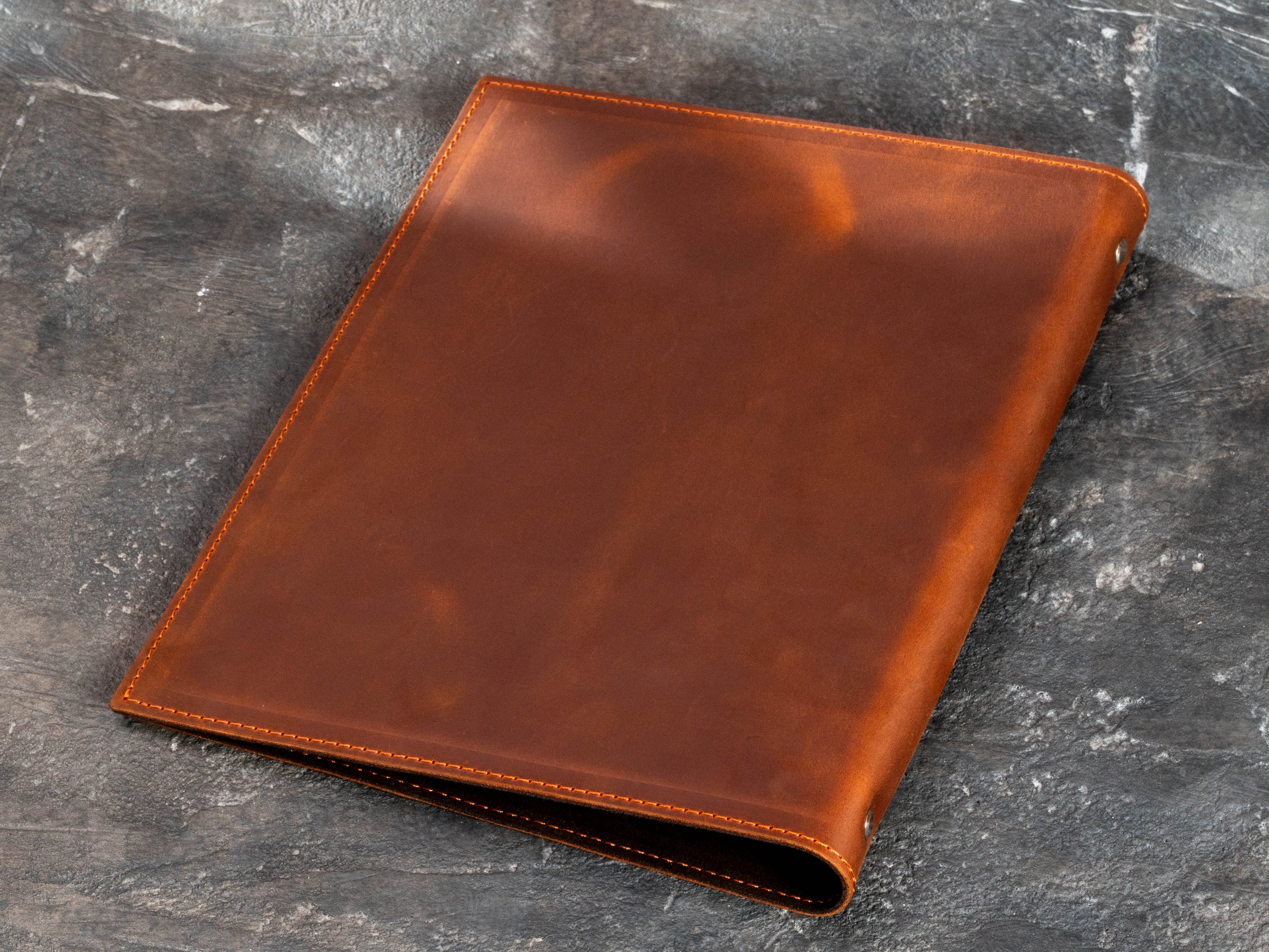 Back view of chestnut brown leather golf binder showing smooth leather surface and stitched edges