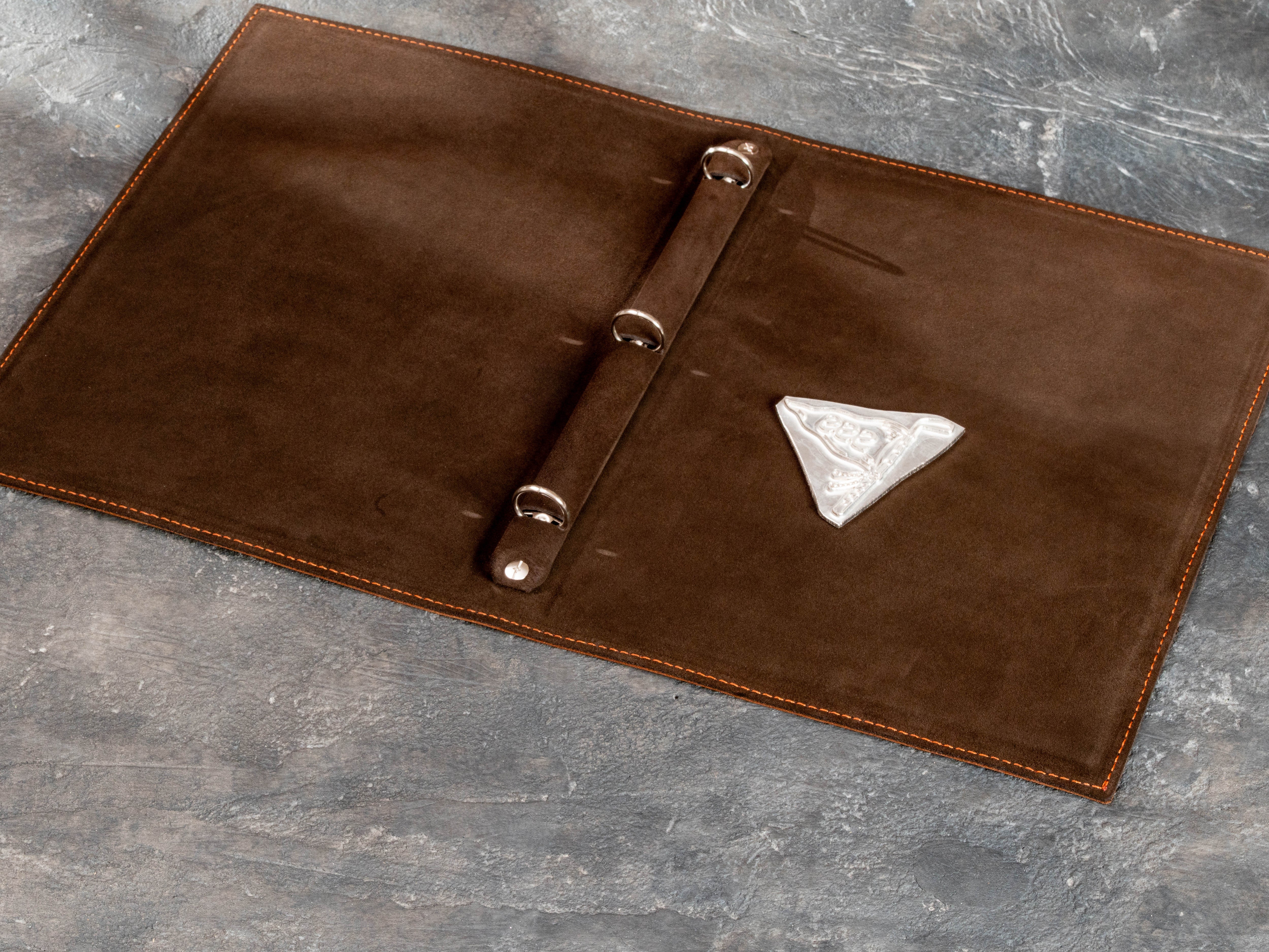 Interior of leather golf binder with three-ring mechanism and custom embossing die used for personalization
