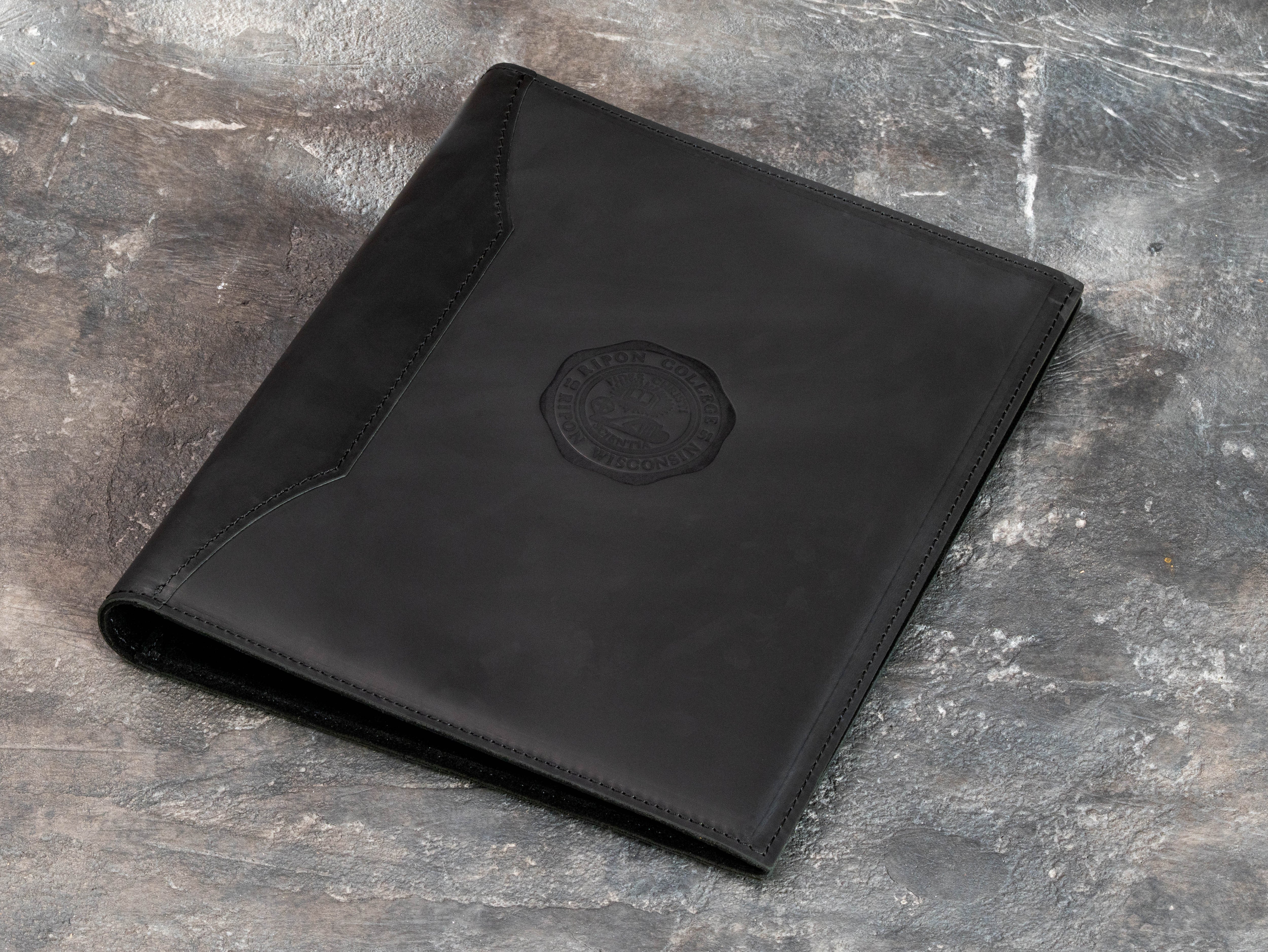 Back view of black leather academic memory binder showing smooth leather surface, reinforced construction and stitched edges