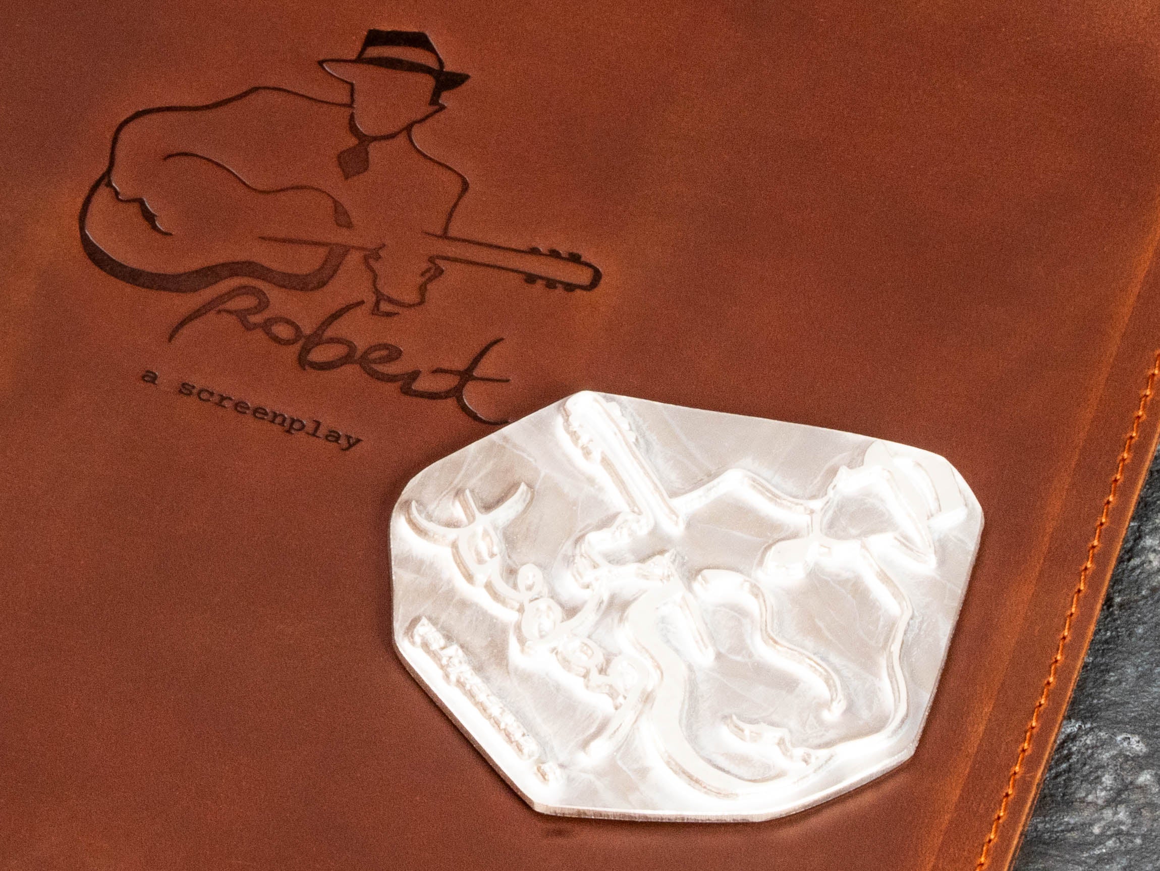 Close-up of custom musician and guitar embossing on brown leather with the matching personalization die