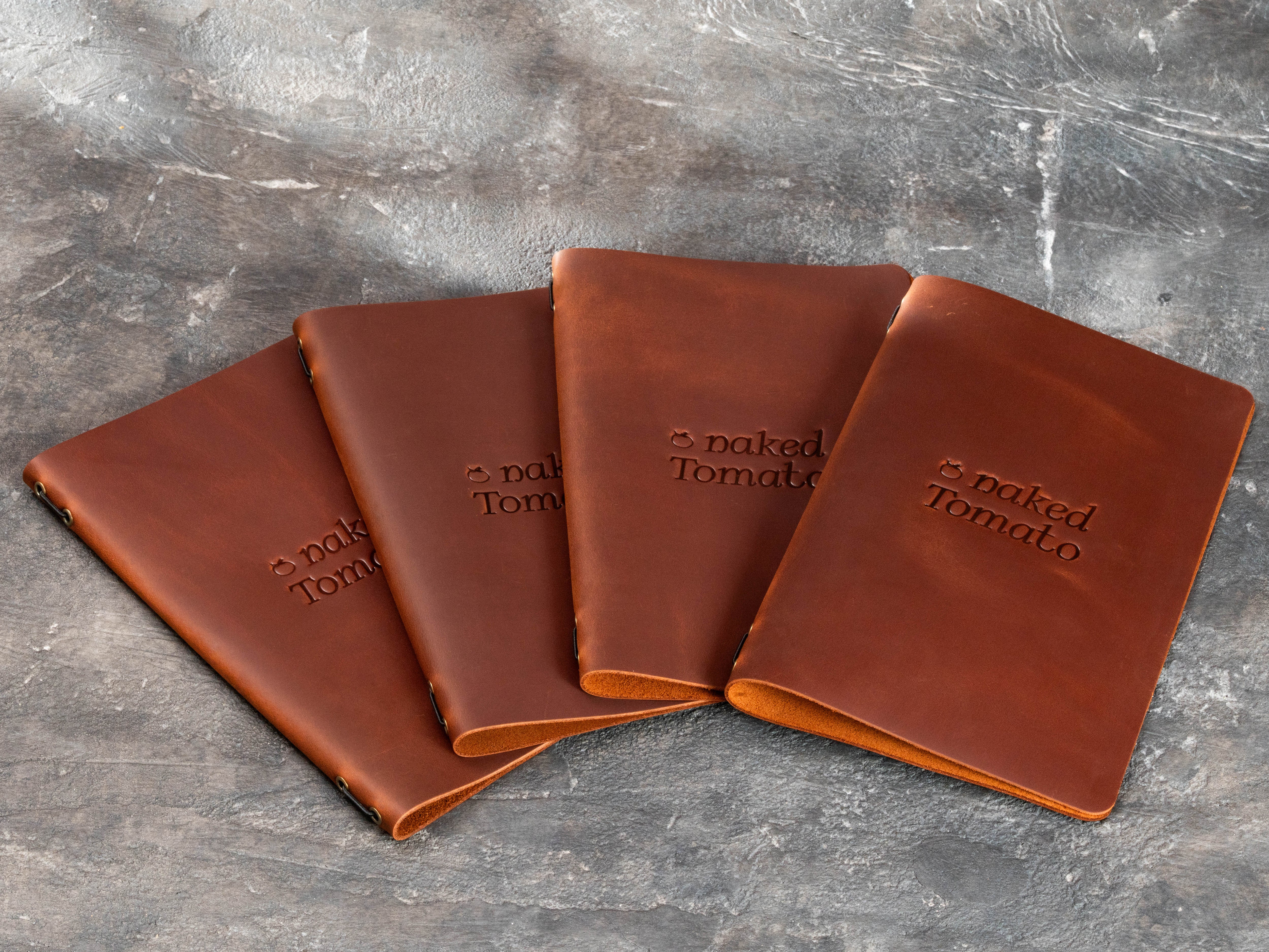 Custom brown leather restaurant menu covers made for Naked Tomato with blind embossed logo in multiple sizes.