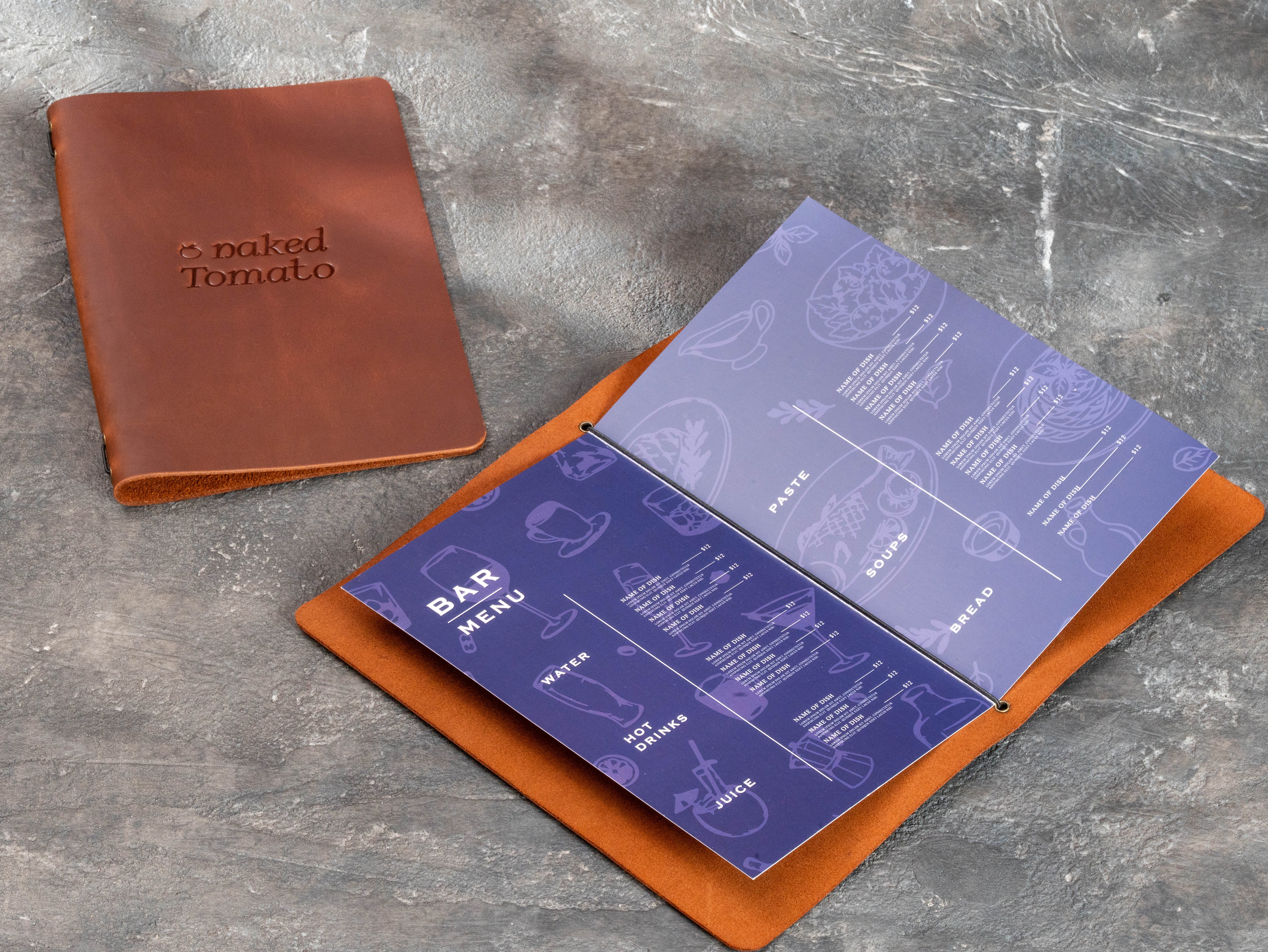 Open brown leather restaurant menu cover with elastic cord holding printed bar and food menu pages, next to a closed branded cover