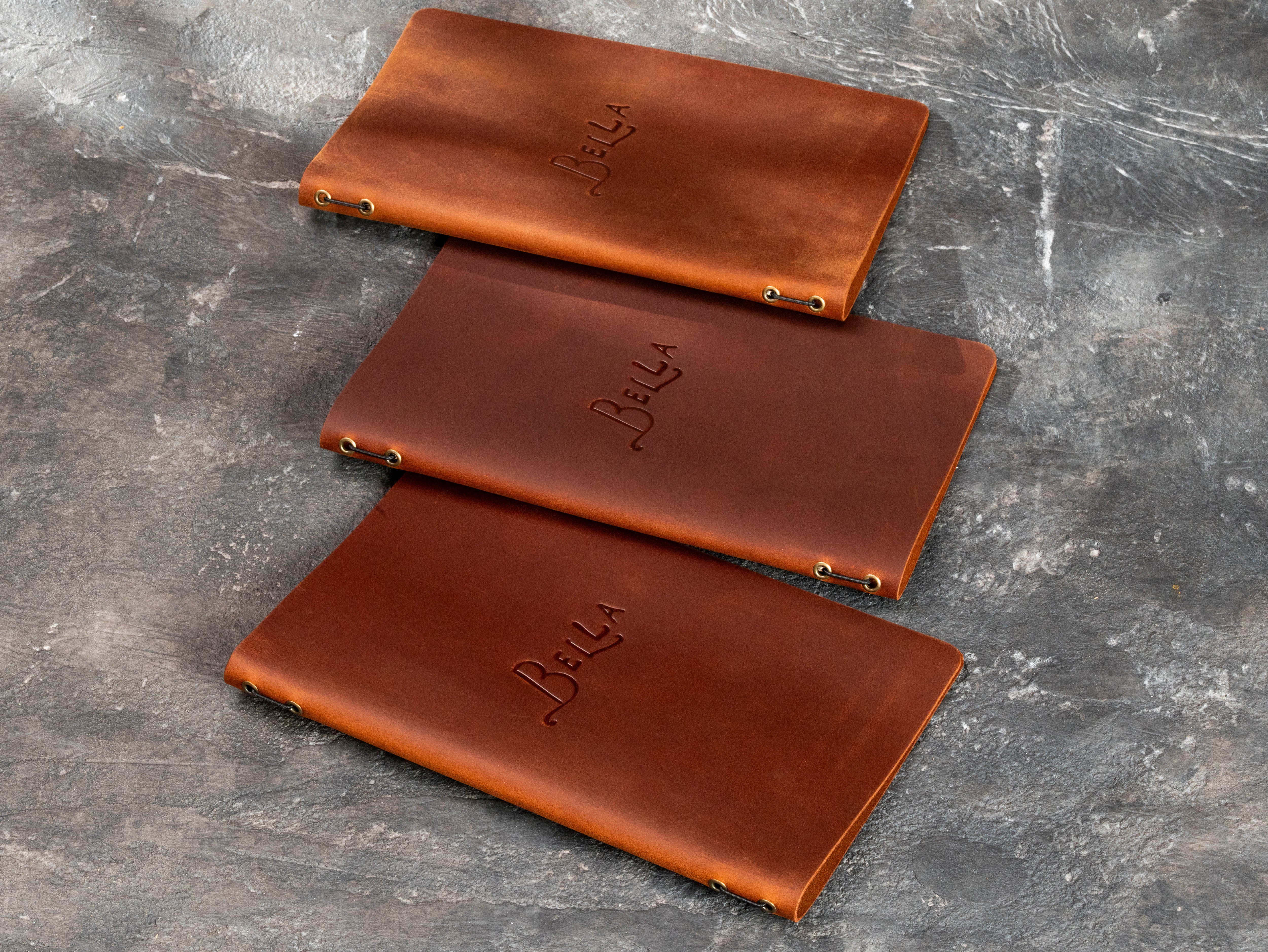 brown leather restaurant menu covers shown from the back with metal eyelets and elastic cord binding