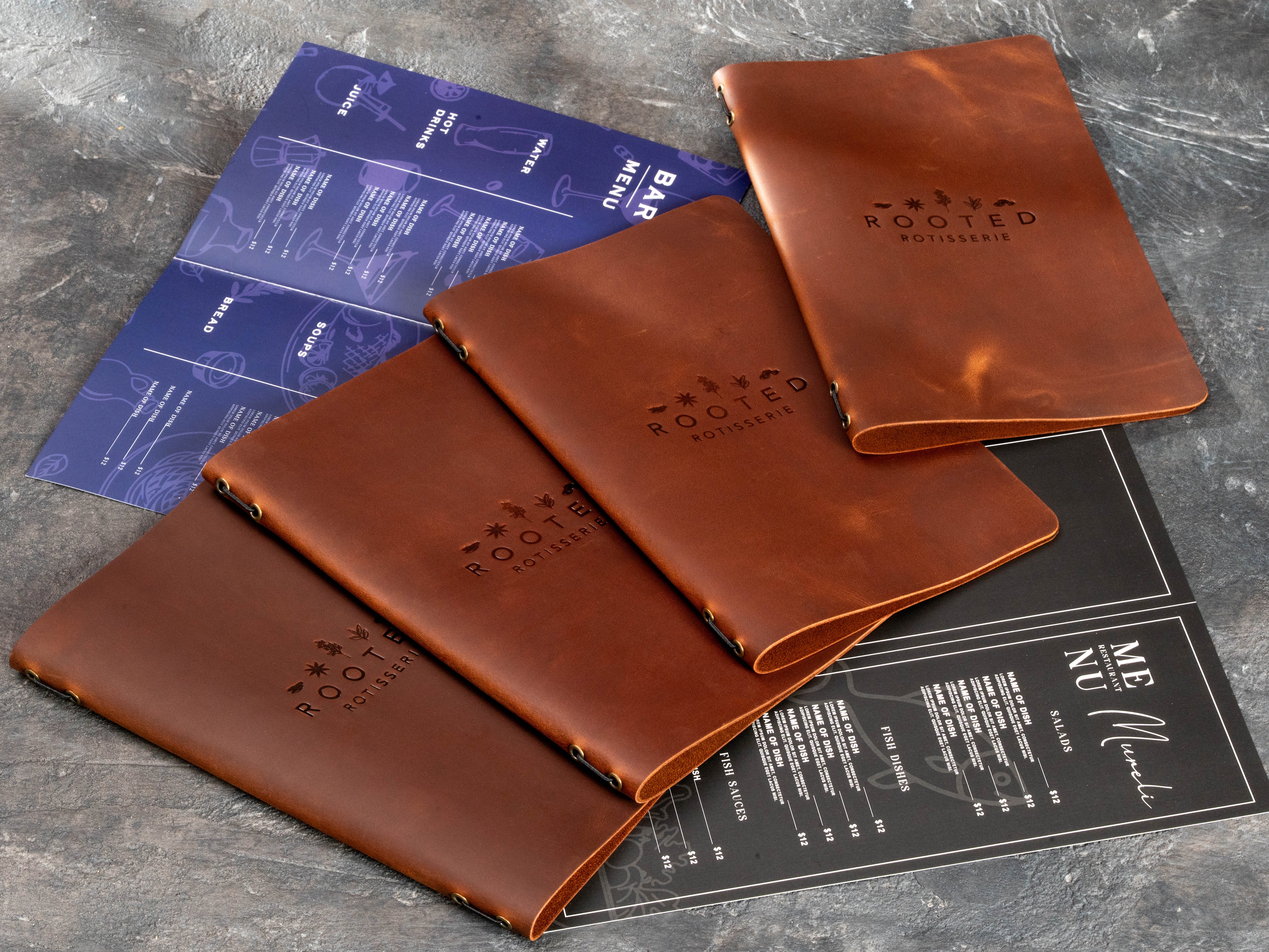 Multiple warm brown restaurant menu books arranged with blind embossed logos and sample menu inserts.