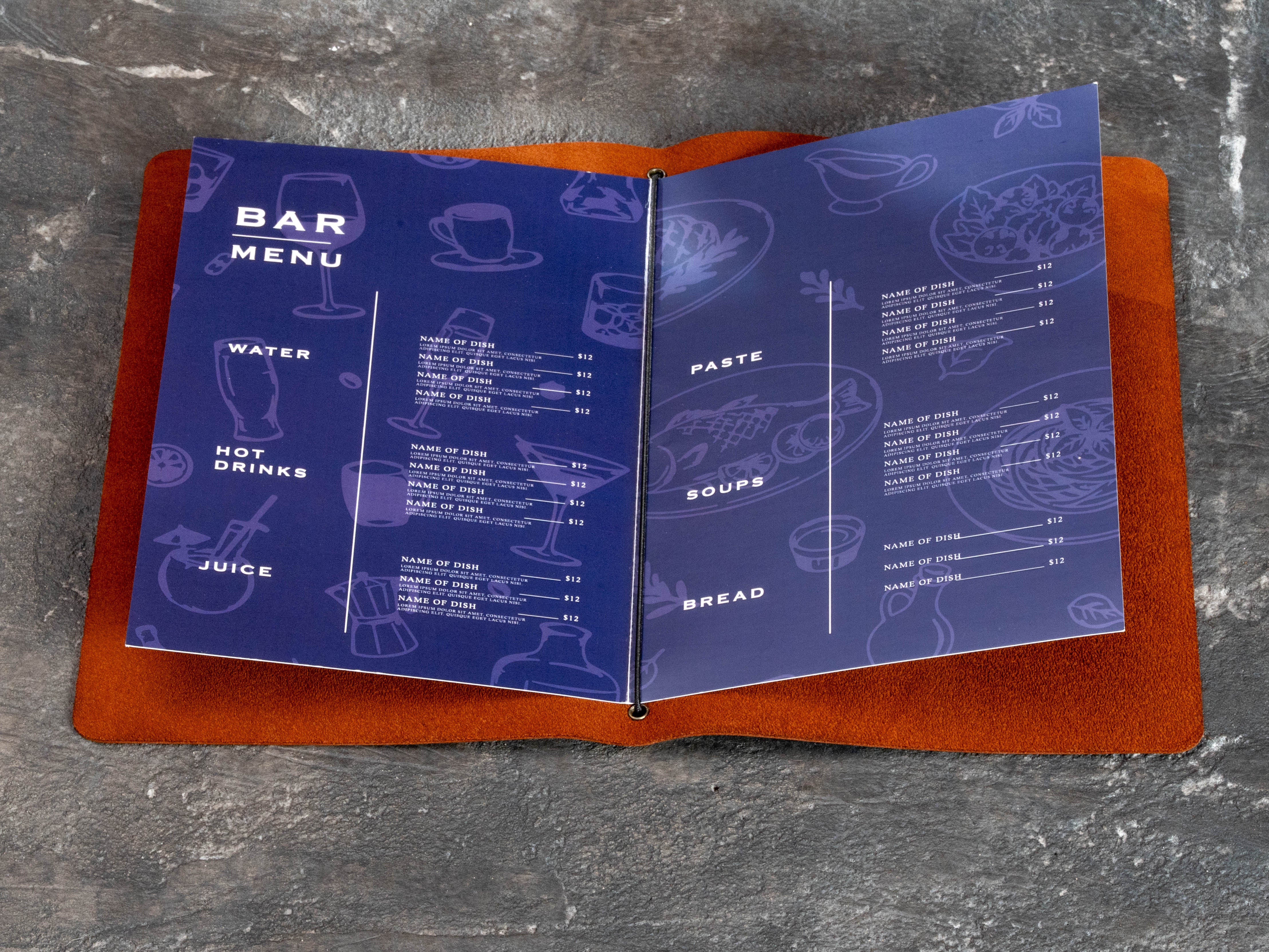 Close view of replaceable restaurant menu pages held inside a warm brown leather cover with elastic binding.