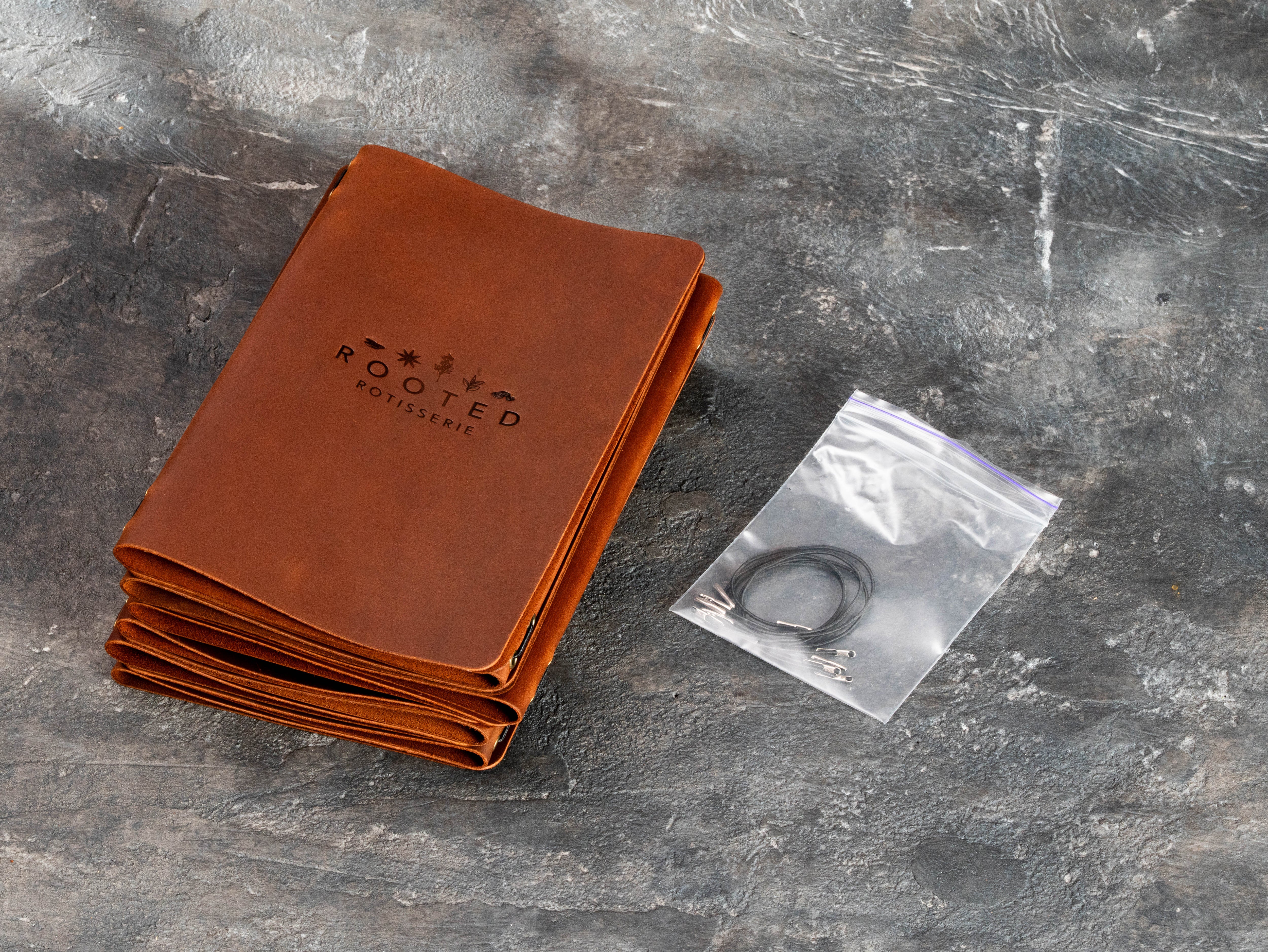 Stack of custom restaurant menu covers with spare elastic cords prepared for future replacement and maintenance